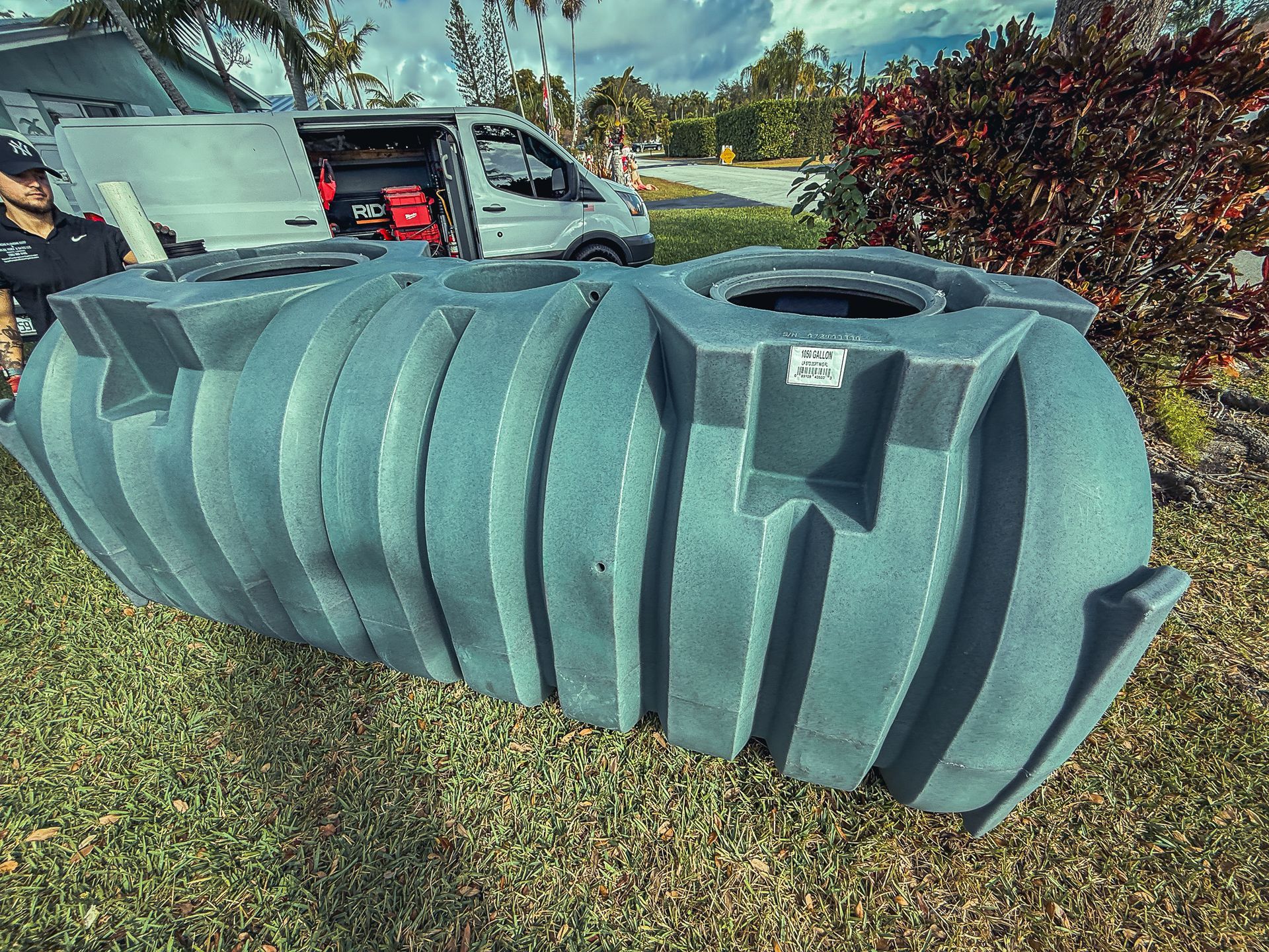A large gray tank is sitting in the grass next to a van.