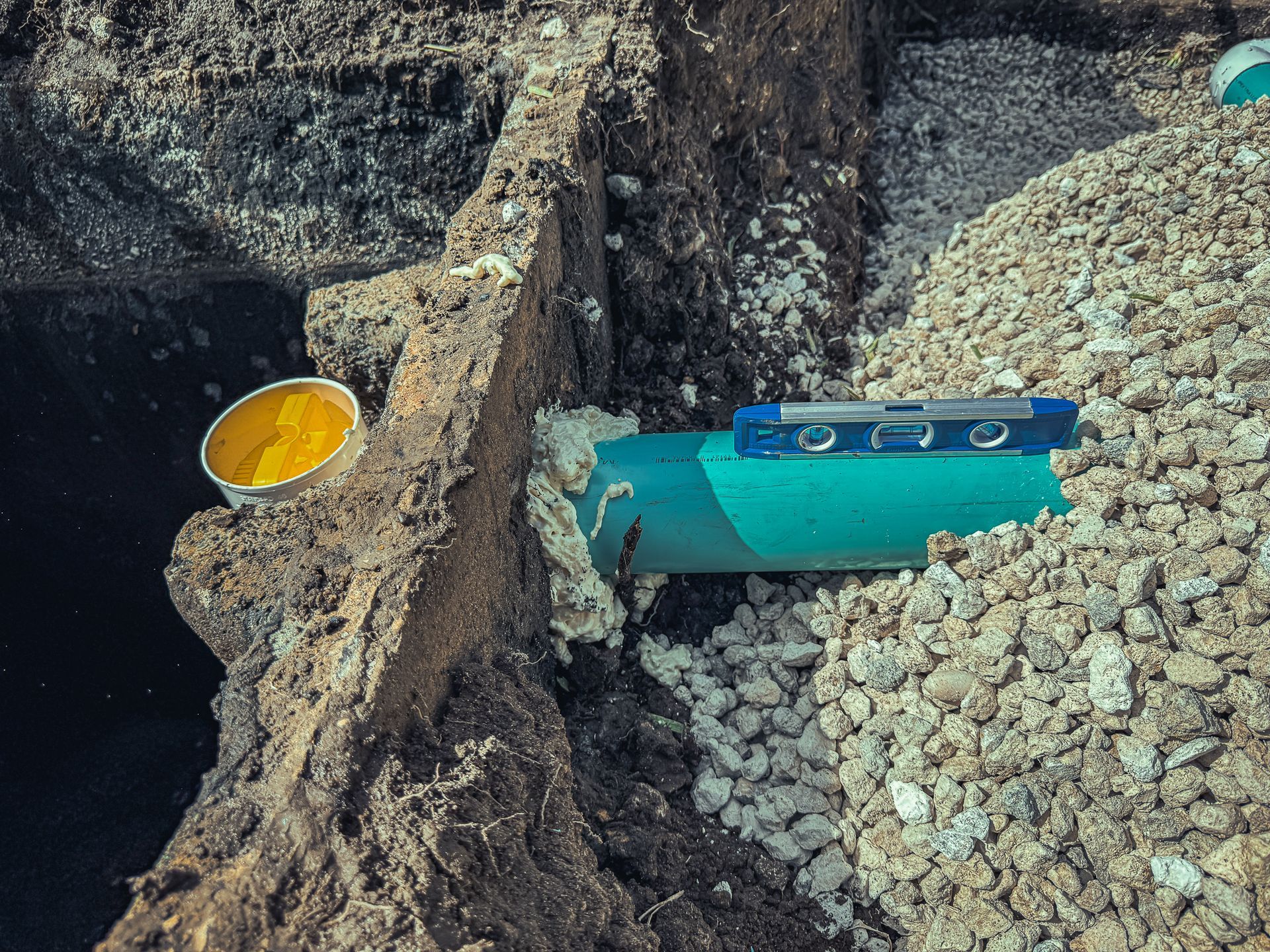 A blue pipe is sitting on top of a pile of gravel.