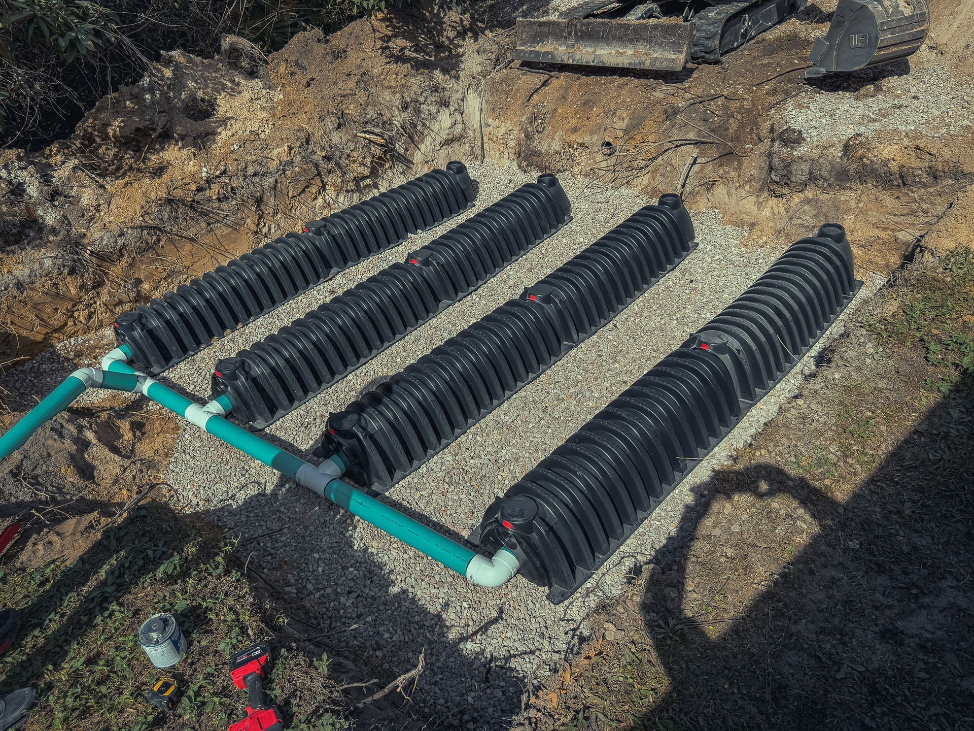 A septic system is being built in the dirt with a bulldozer in the background.