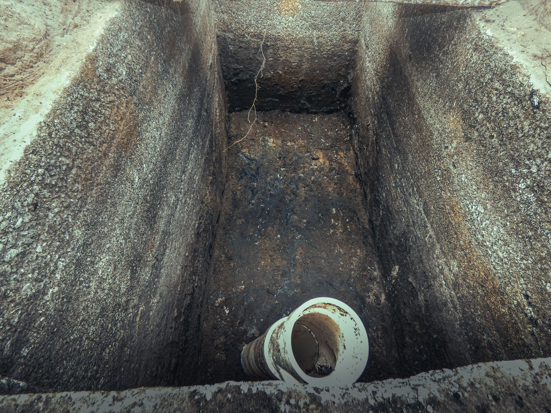 A hole in the ground with a white pipe in it