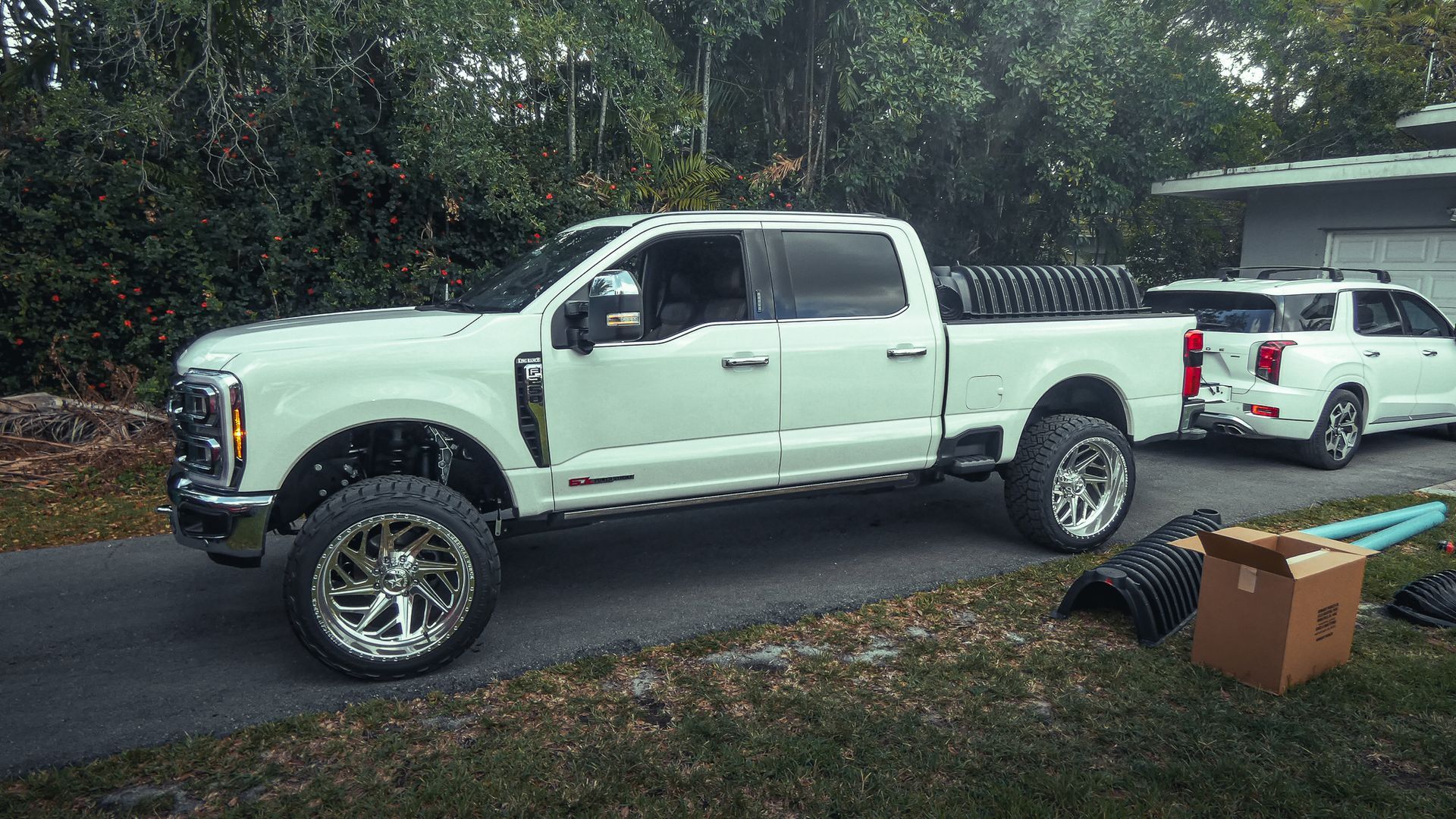 A white truck is parked on the side of the road next to a white truck.