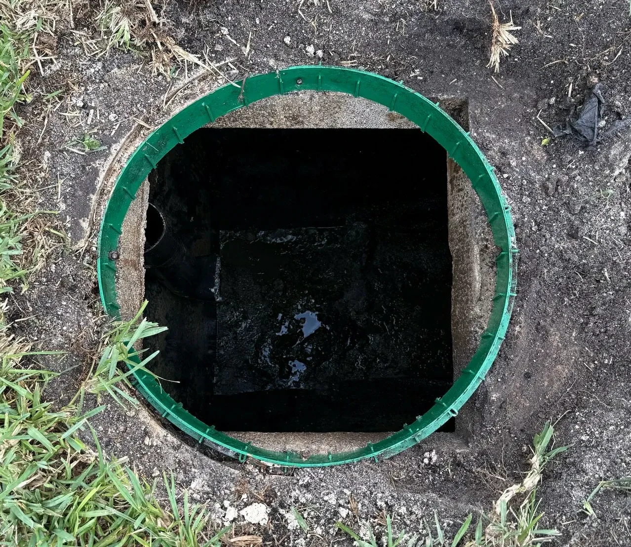 A hole in the ground with a green ring around it