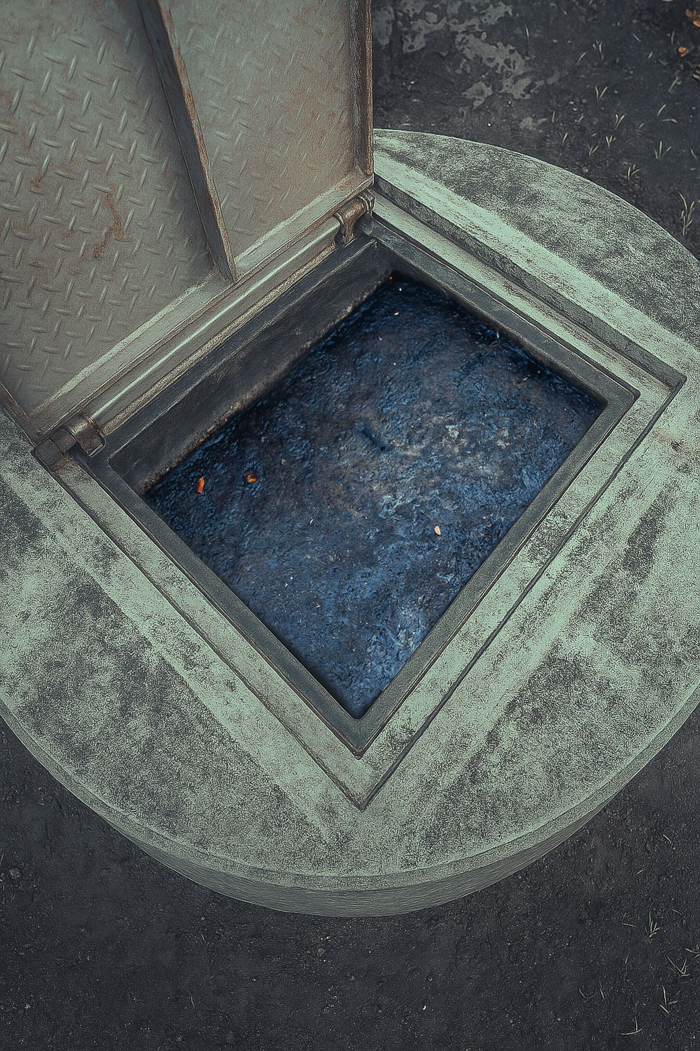 A manhole cover is open and filled with water.