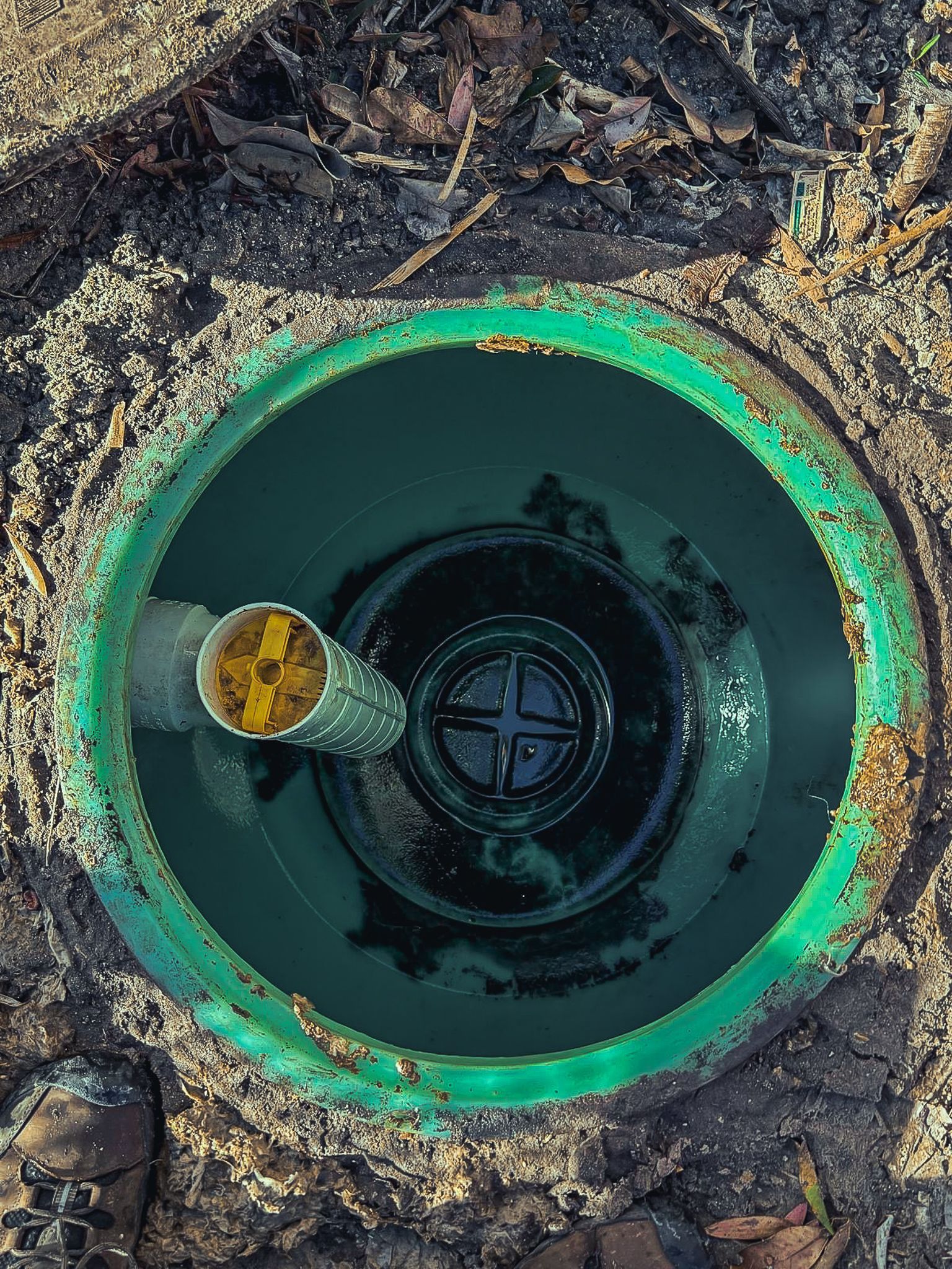 A green drain with a hose coming out of it.