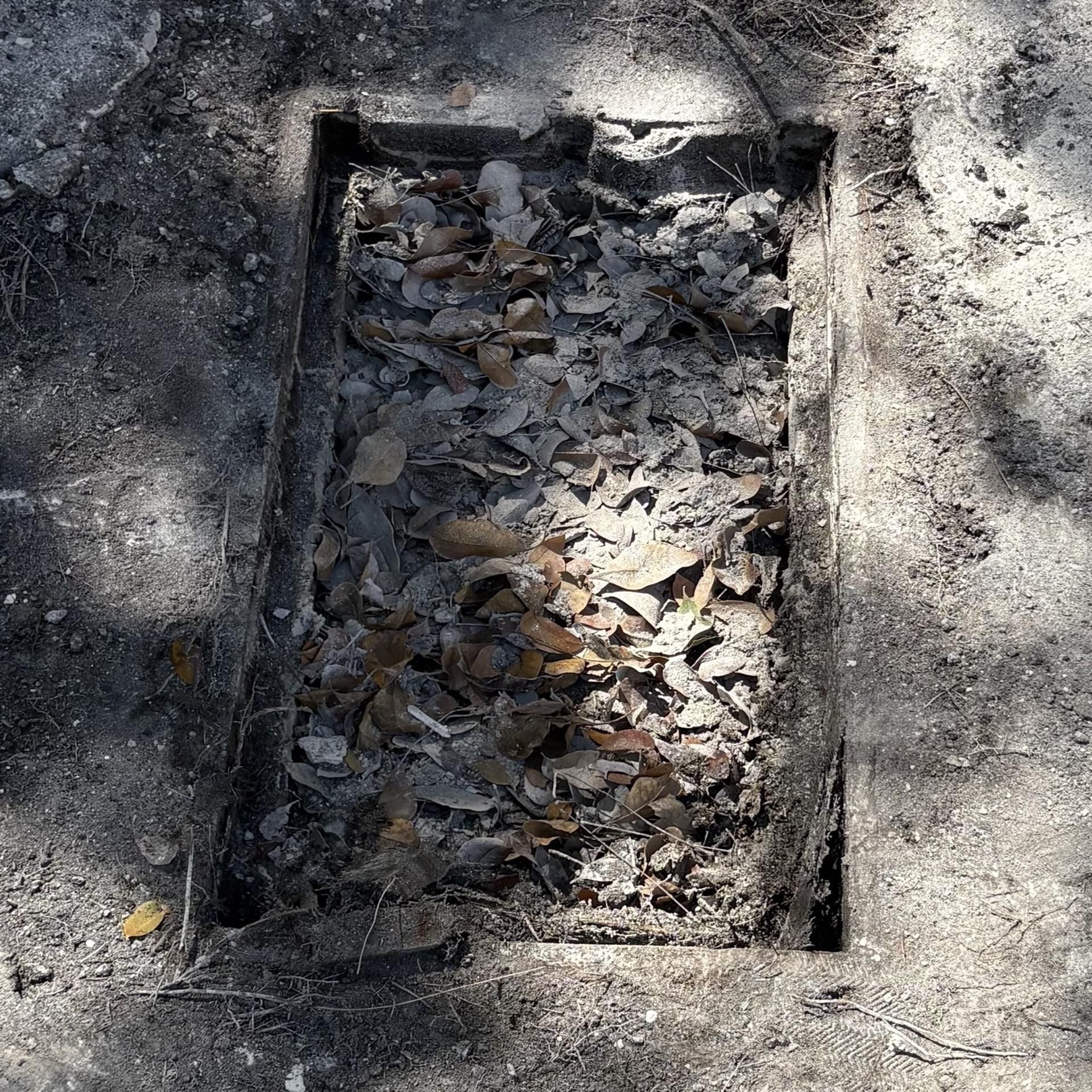 A close up of a hole in the ground with a rock in it.