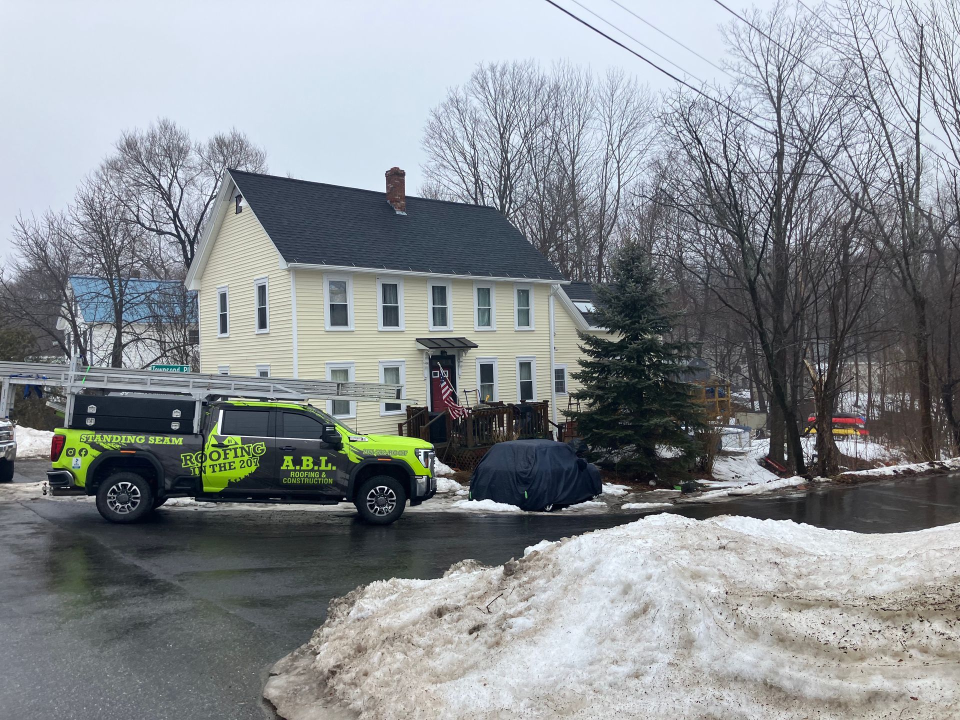 A truck is parked in front of a house in the snow.
