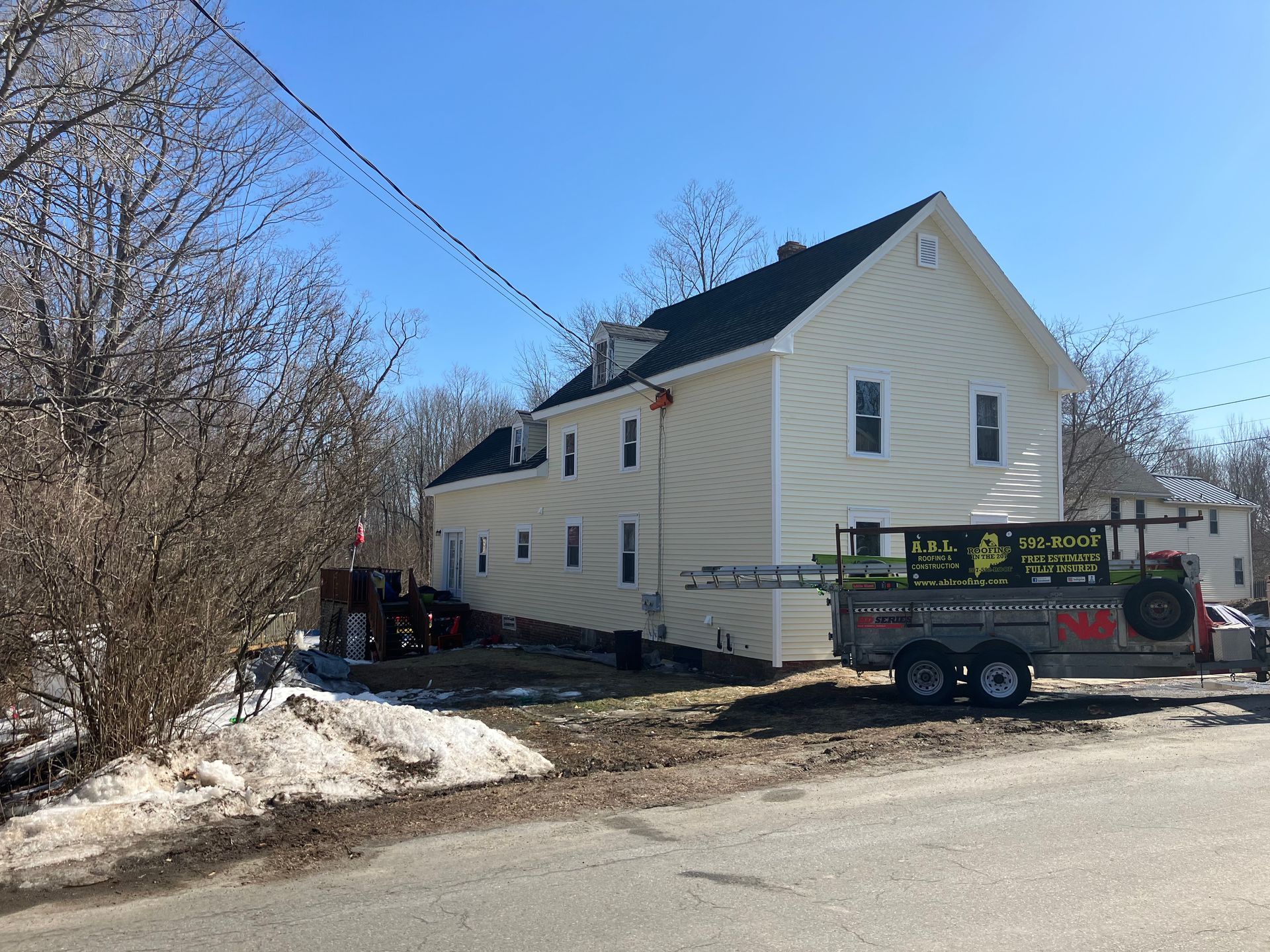 A white house with a trailer parked in front of it.