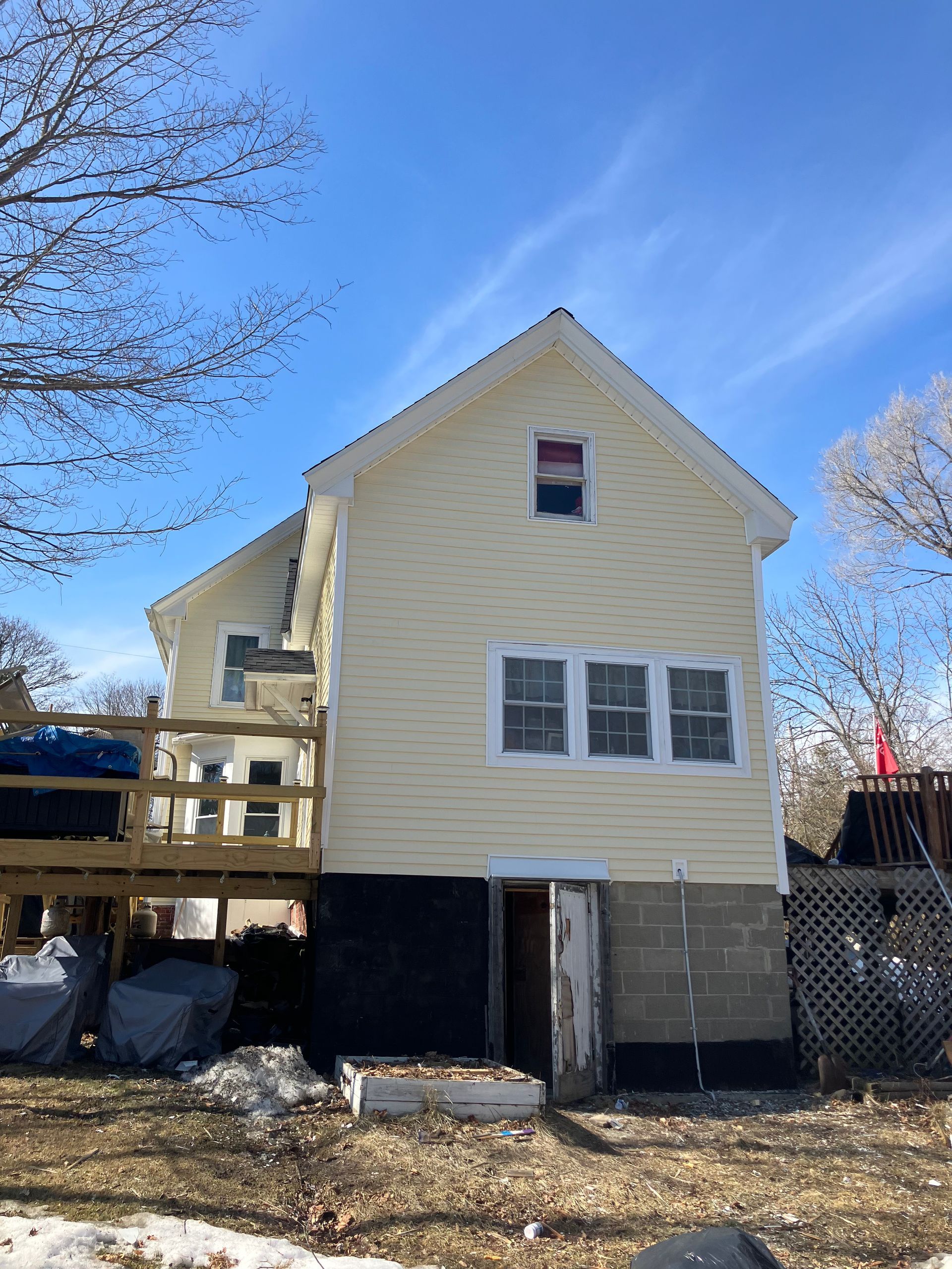 A yellow house with a deck and a blue sky in the background.