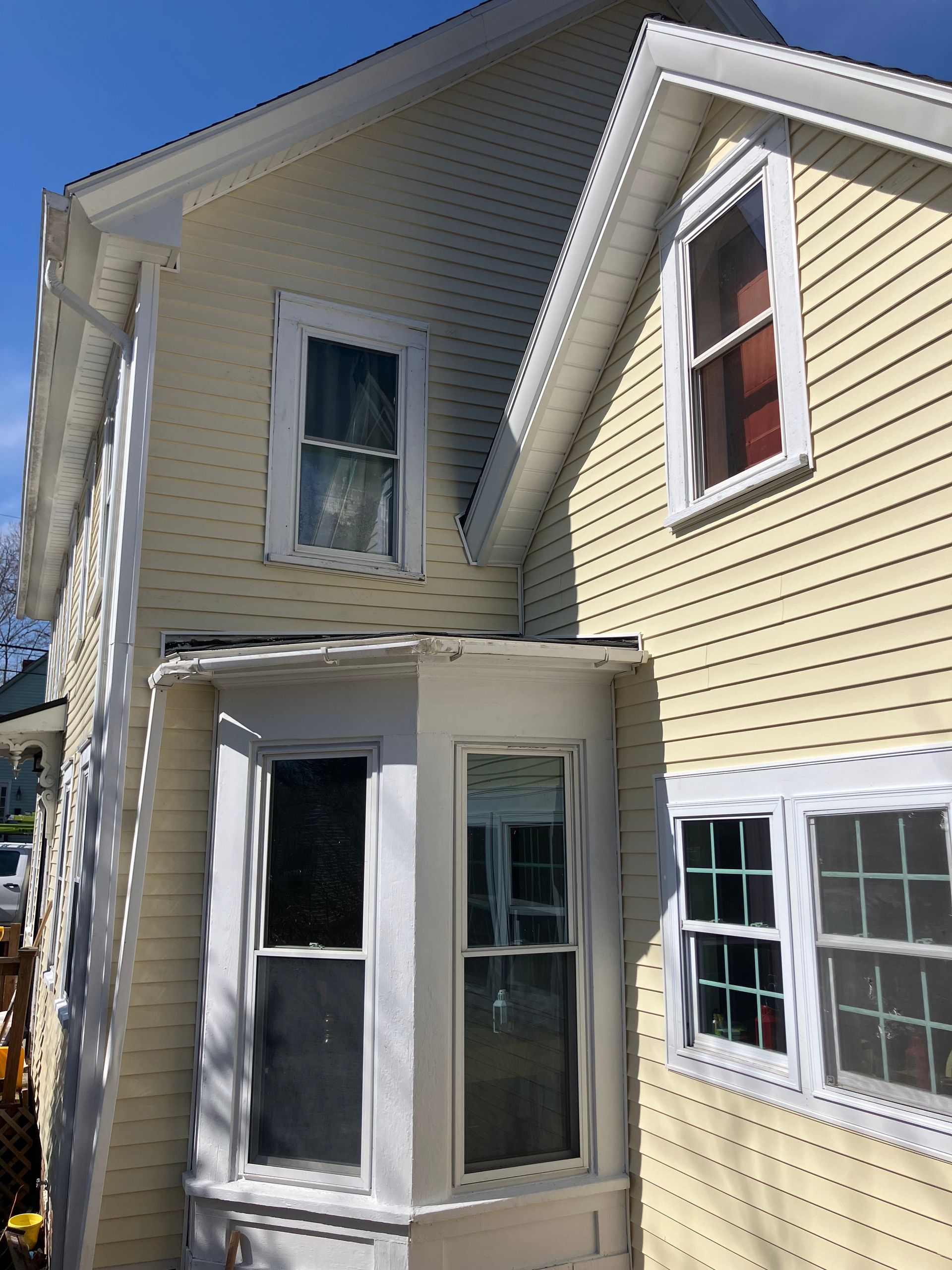 A yellow house with white windows and a bay window