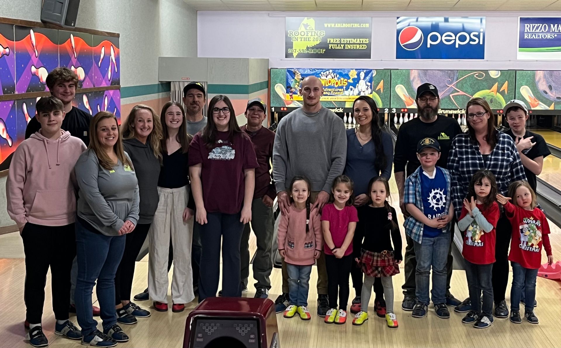 A large group of people are posing for a picture in a bowling alley.
