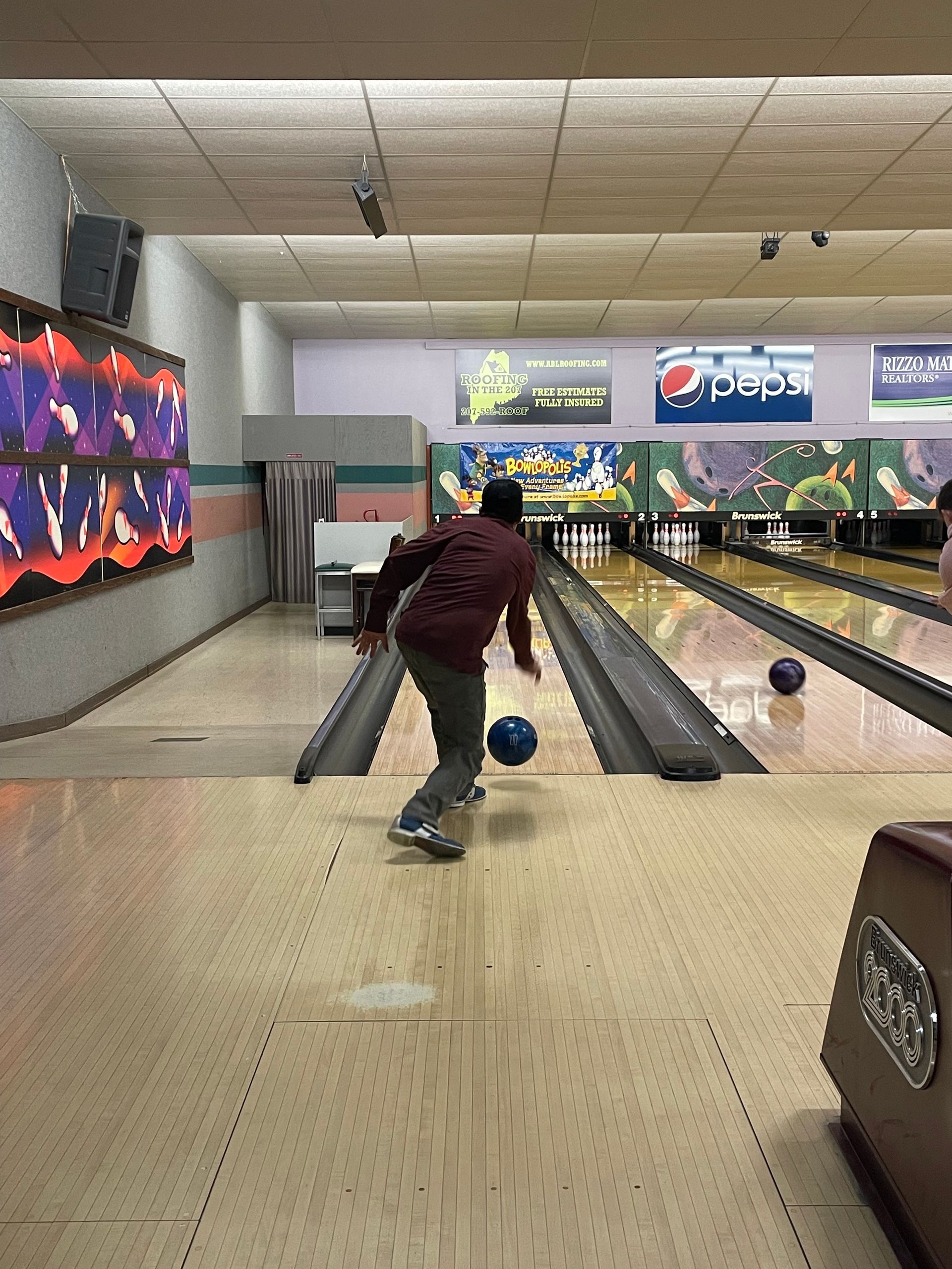 A man is throwing a bowling ball down a bowling alley.
