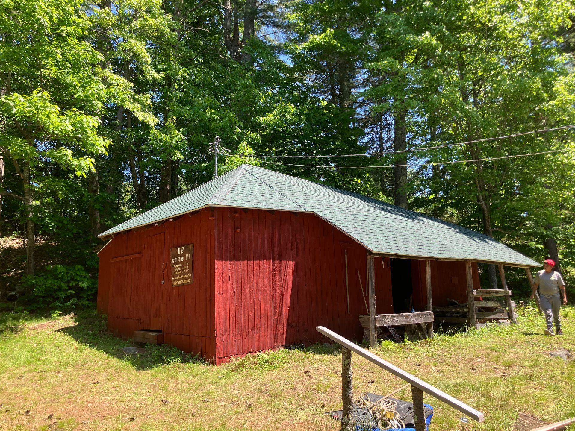 A red barn with a green roof is in the middle of a grassy field.