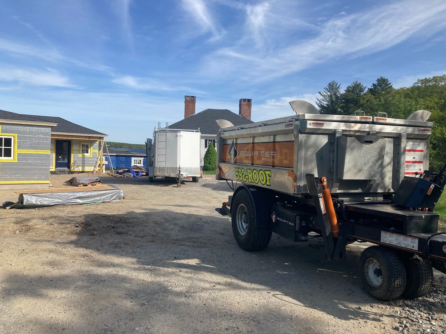 A dump truck is parked in front of a house under construction.