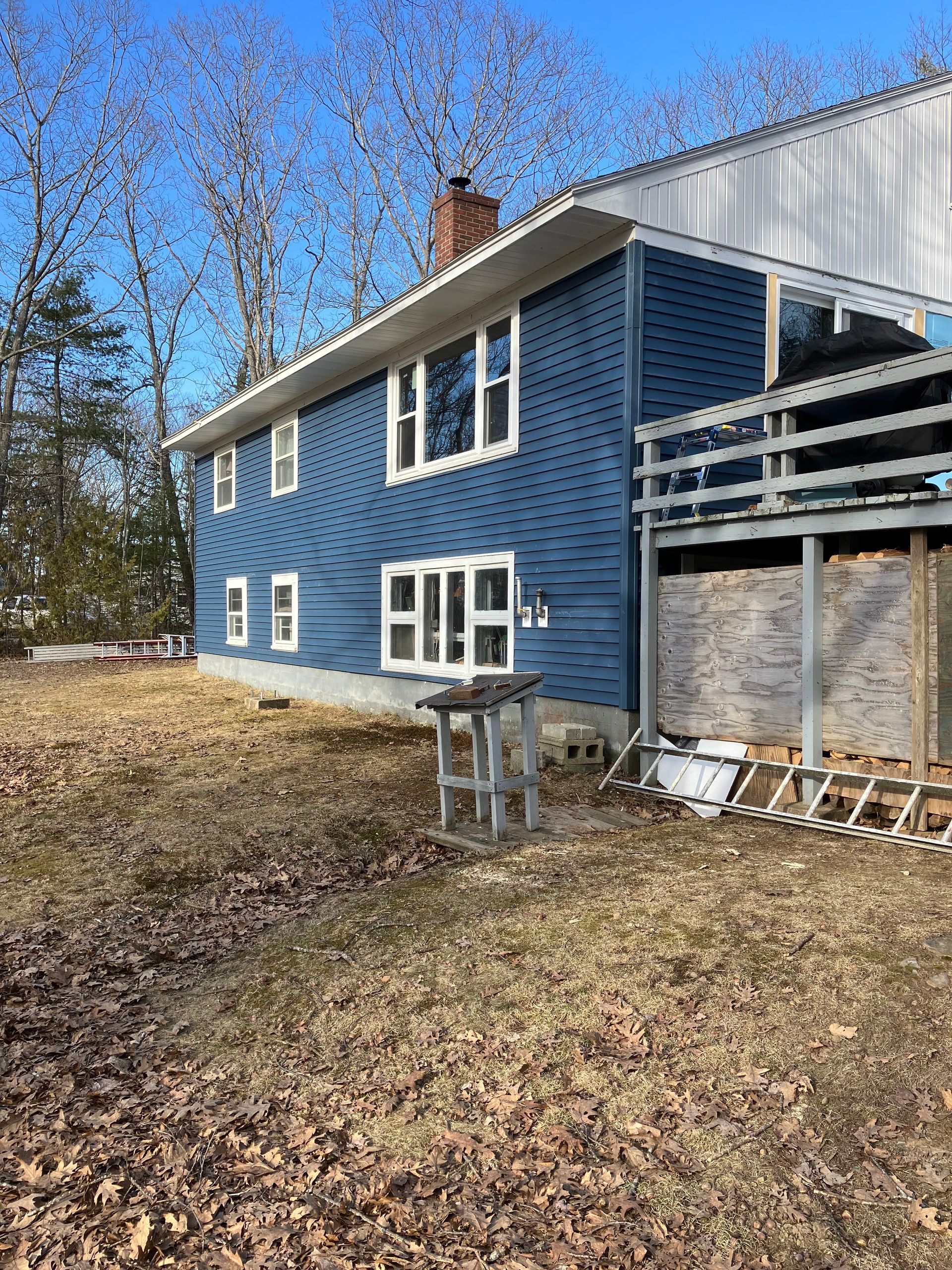 A blue house with white windows is sitting in the middle of a field.