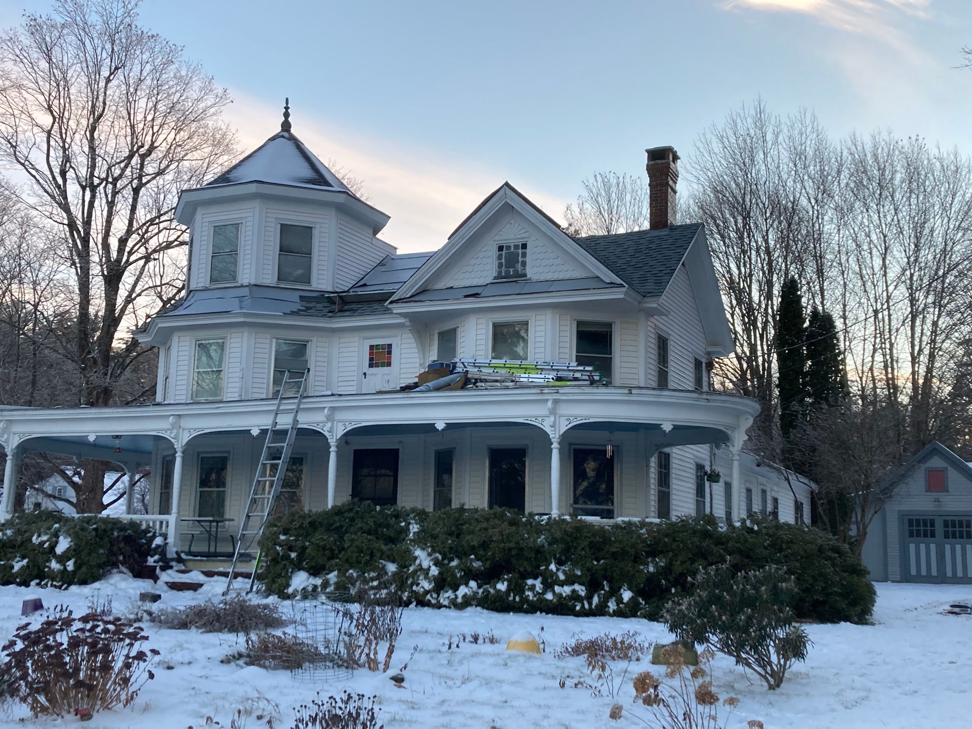 A large white house with a porch in the snow