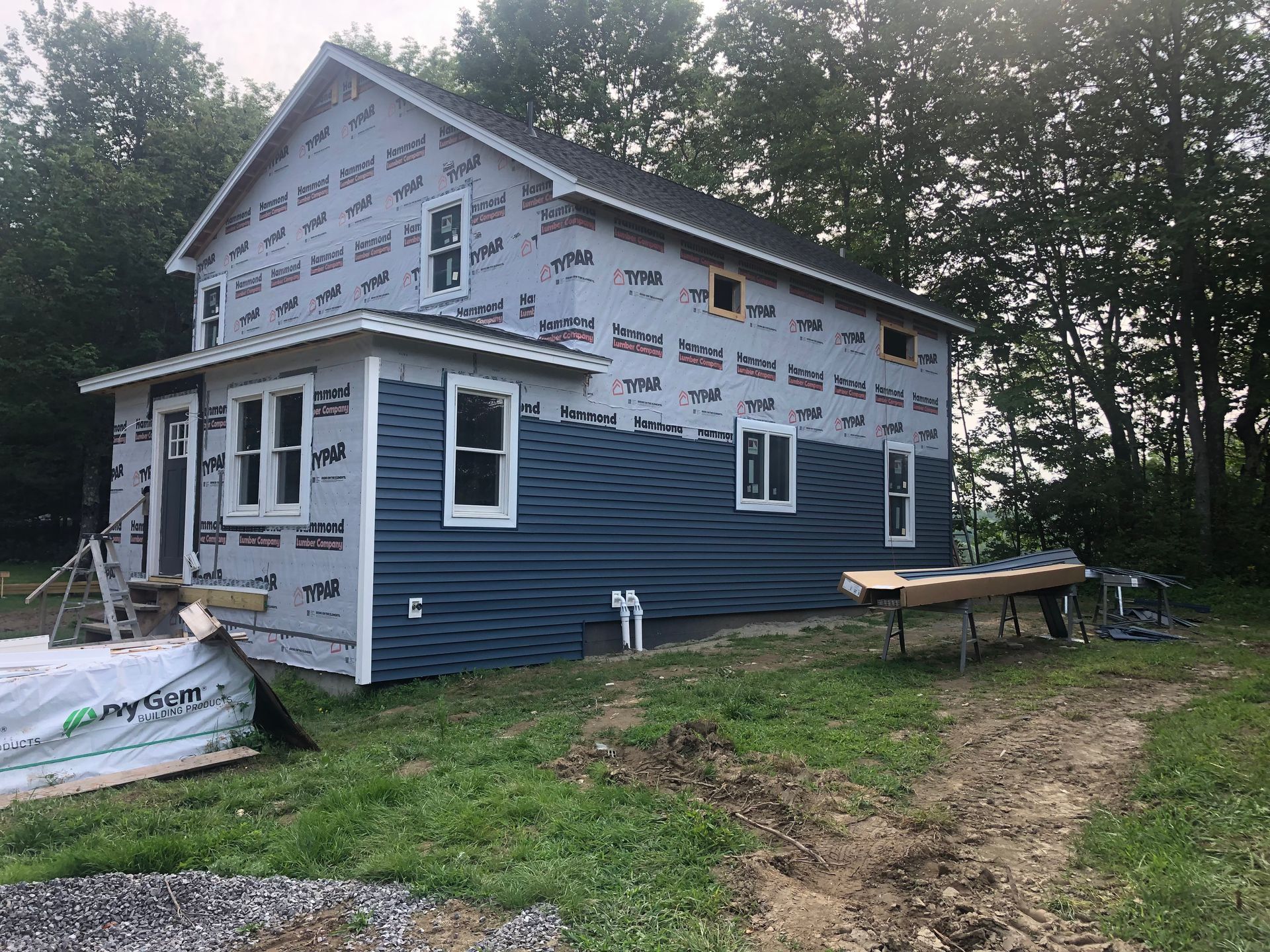 A blue house is being built in the middle of a grassy field.