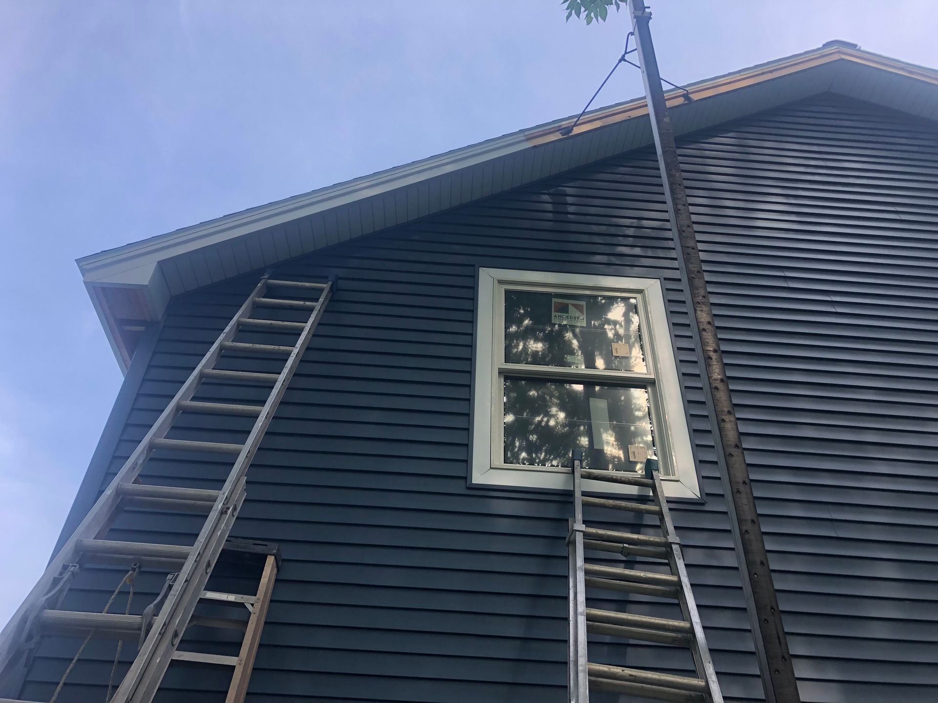 A ladder is sitting on the side of a house next to a window.