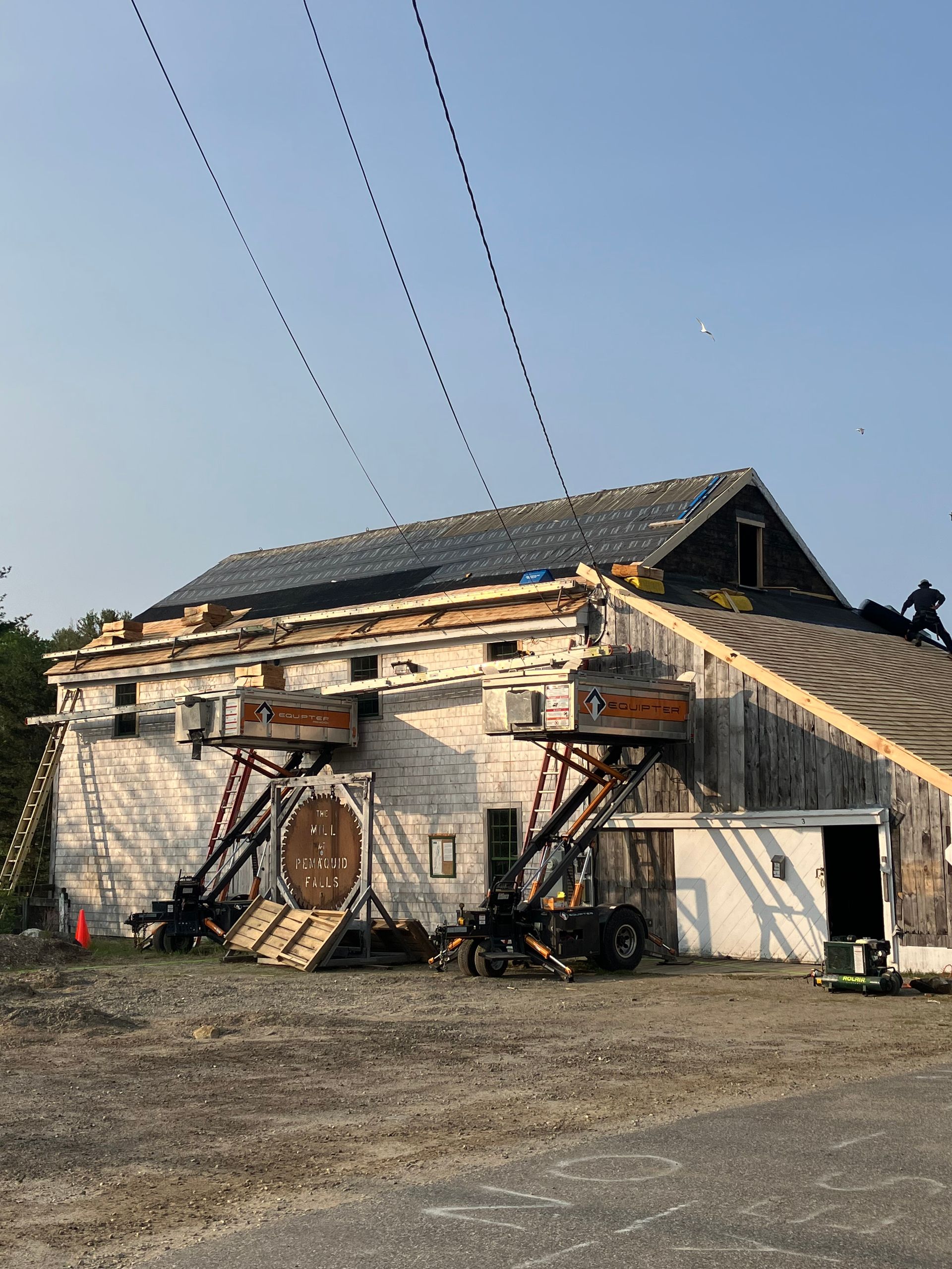 A large white barn with a roof that is being repaired