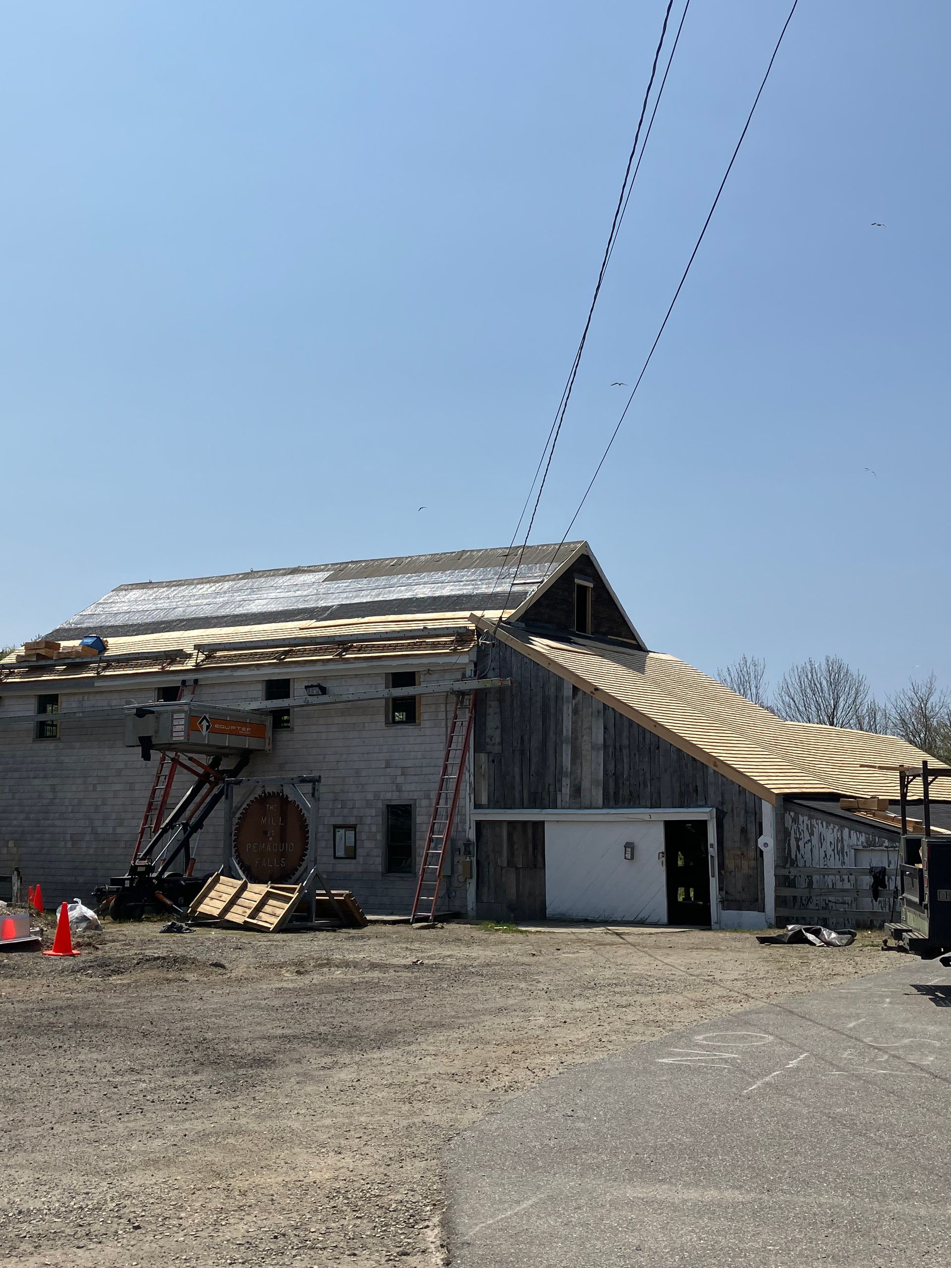 A building with a wooden roof is being built in a dirt field.