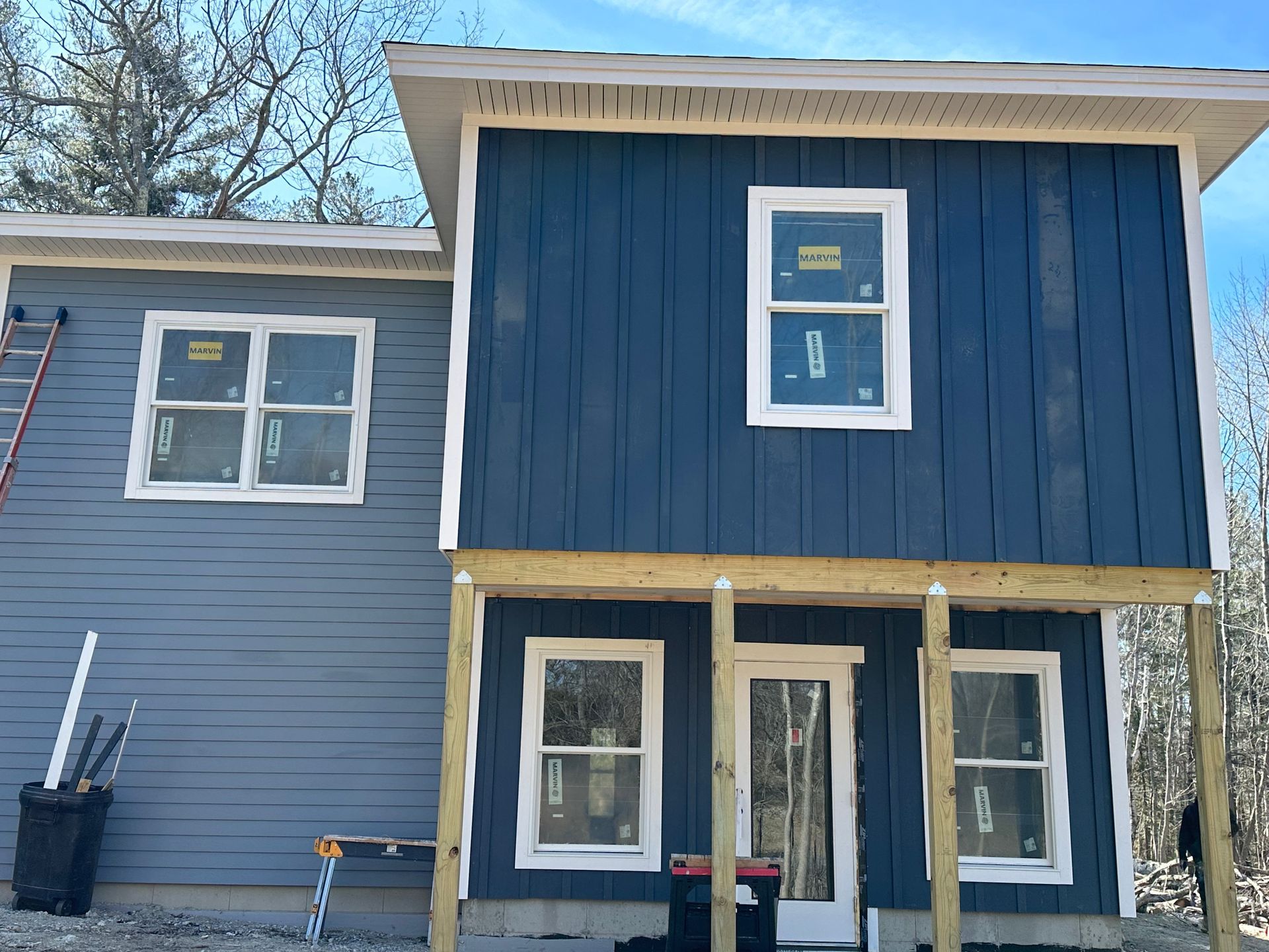 A blue house with white windows is being built.
