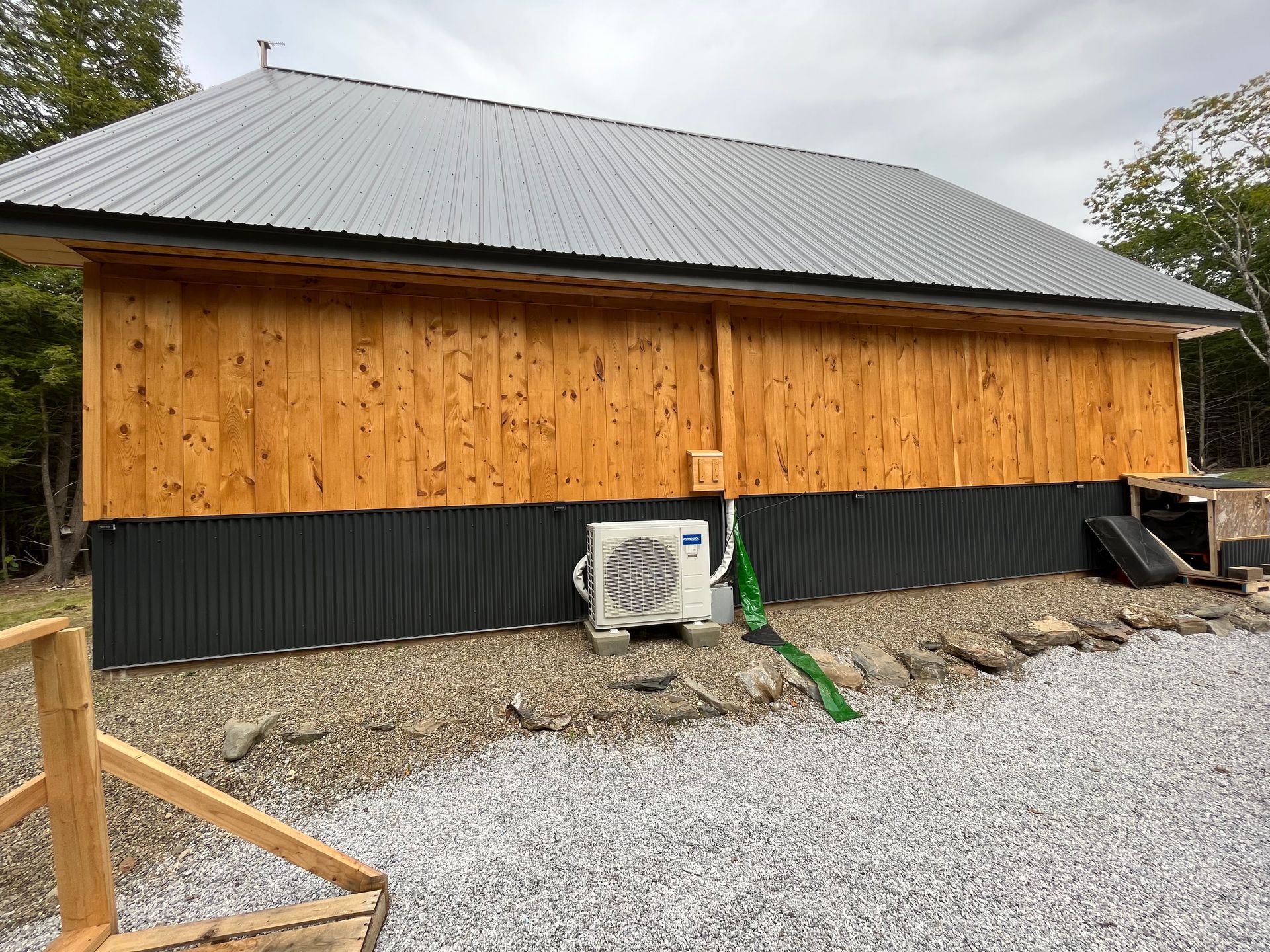 A large wooden building with a metal roof and a small air conditioner on the side.