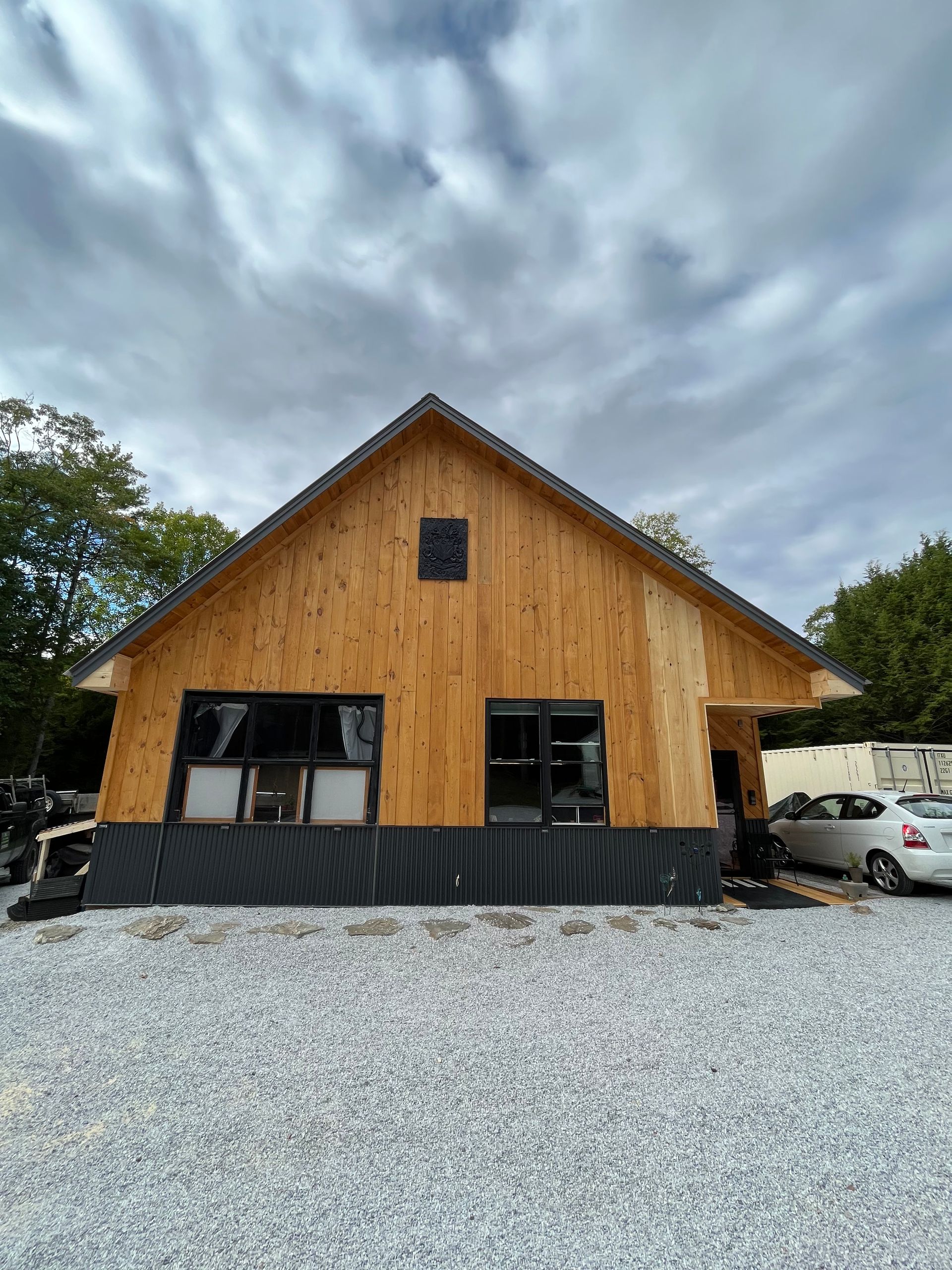 A wooden house is being built in a gravel lot.