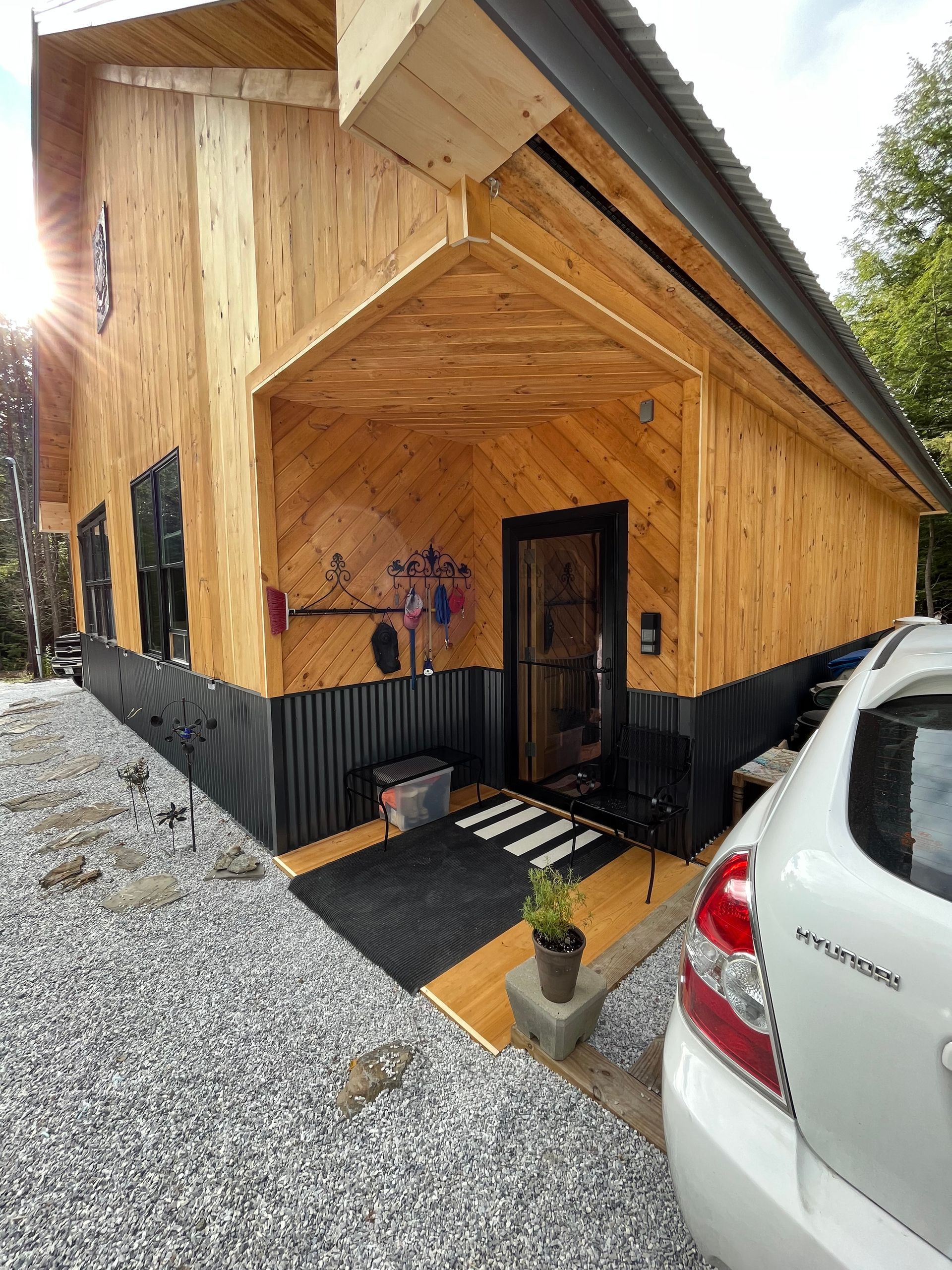 A car is parked in front of a wooden house.