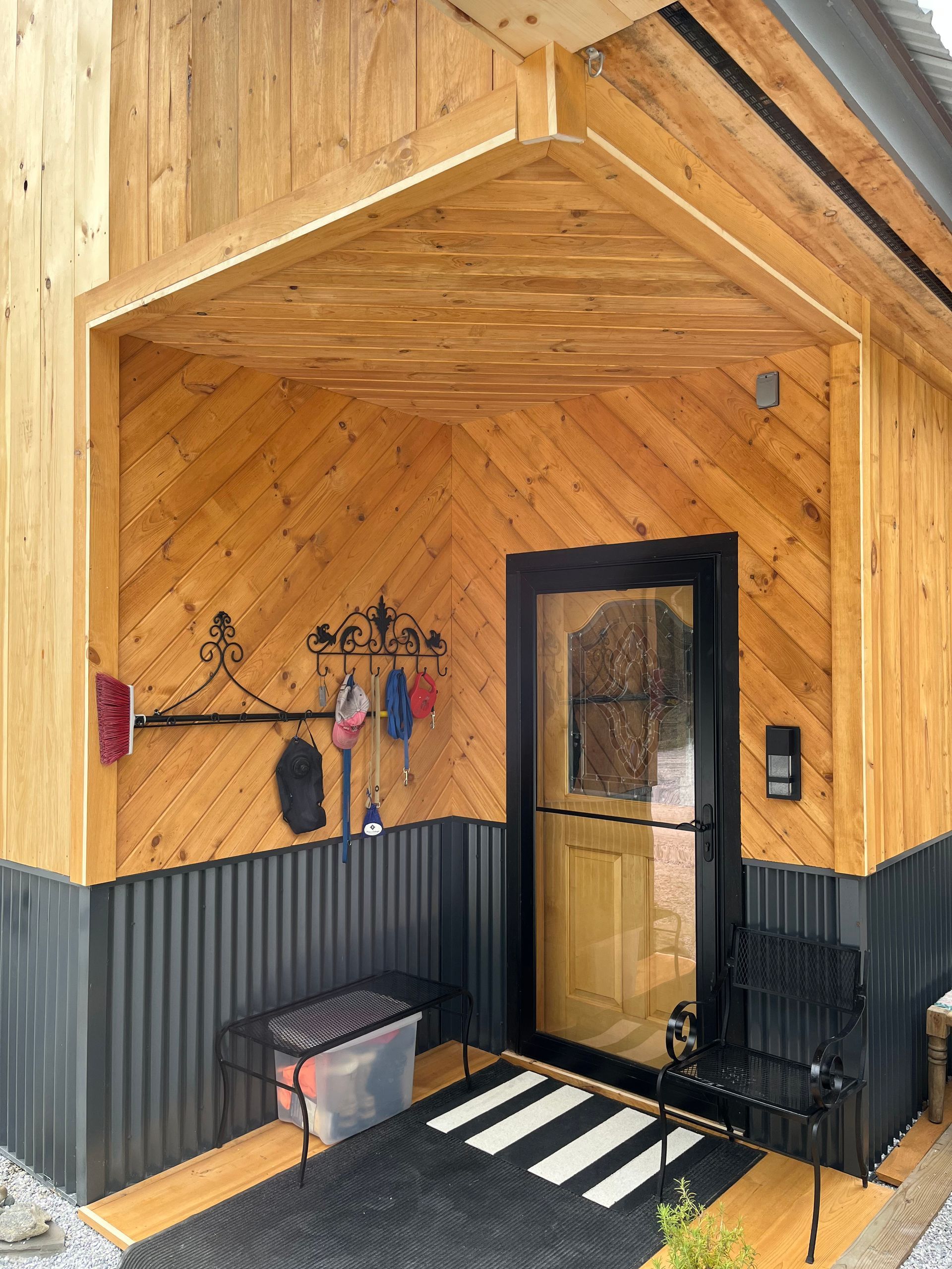 A wooden house with a door and a covered porch.
