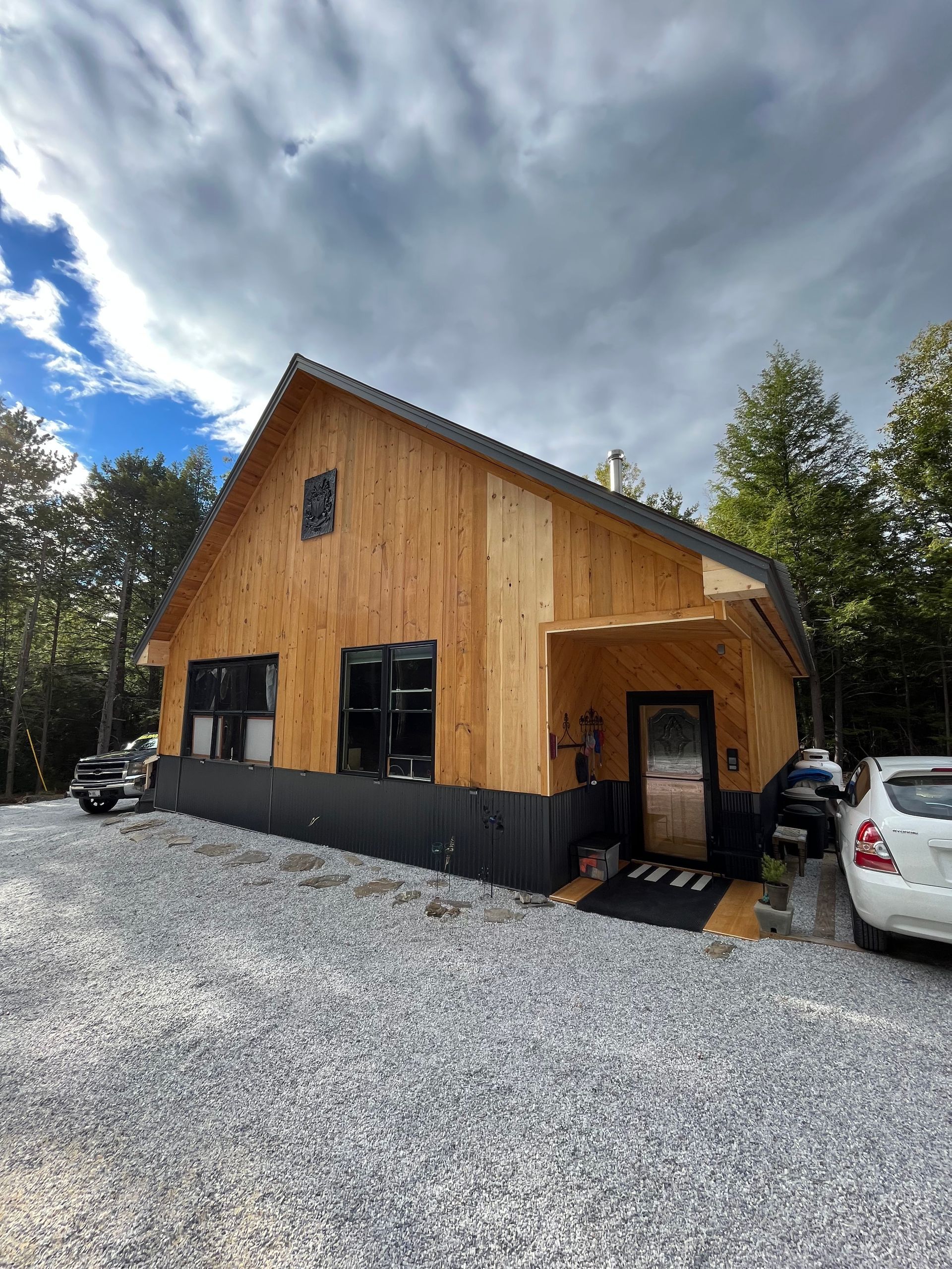 A large wooden house is sitting on top of a gravel lot.
