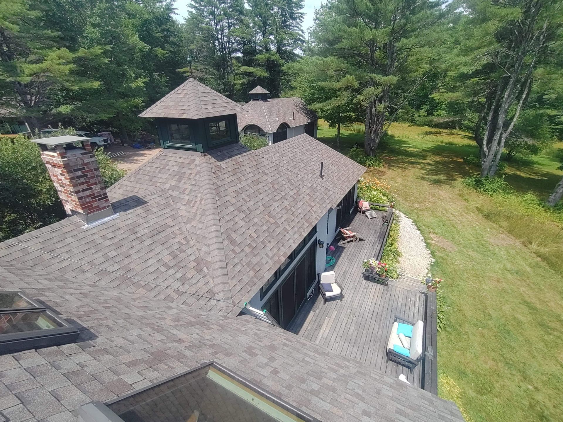 An aerial view of a house with a roof that is surrounded by trees.