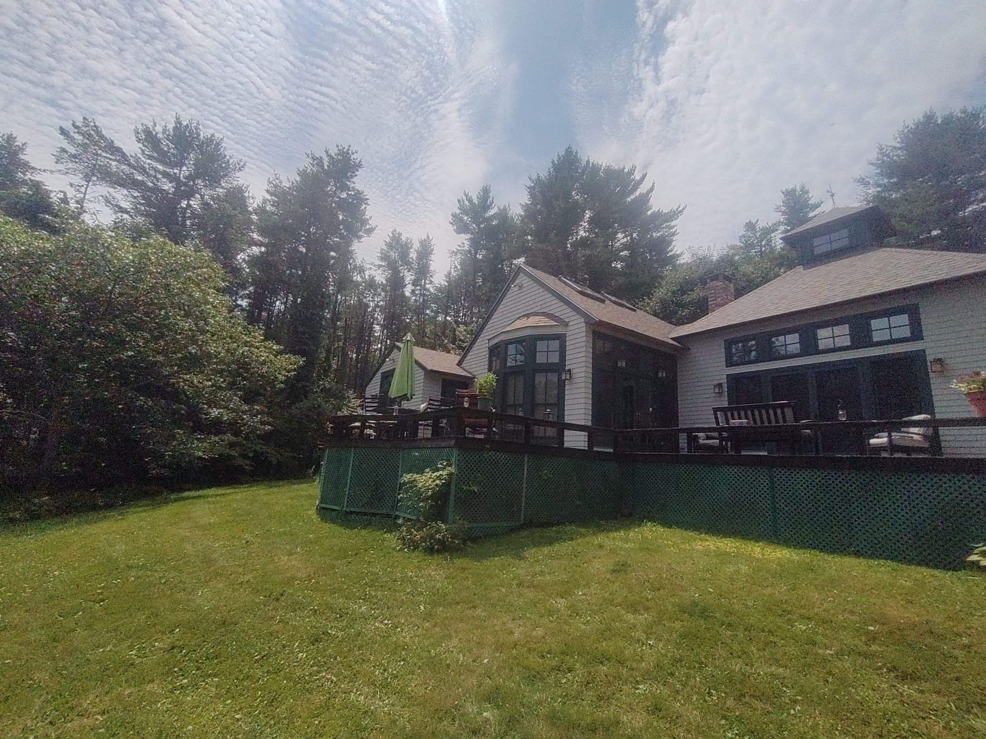 A house with a large lawn in front of it and trees in the background.
