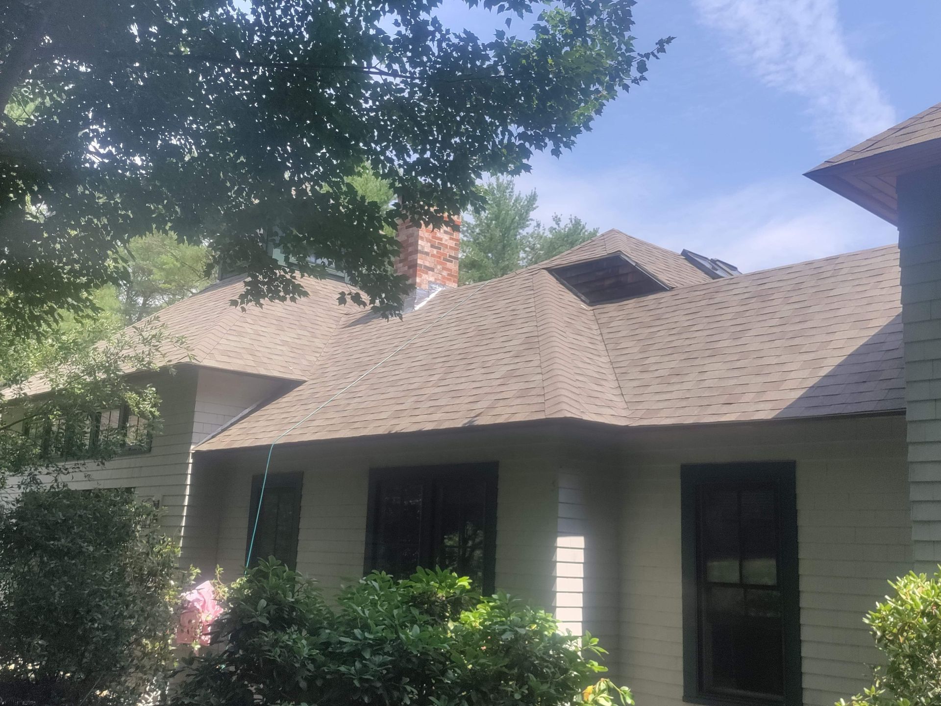 A white house with a brown roof and a chimney.