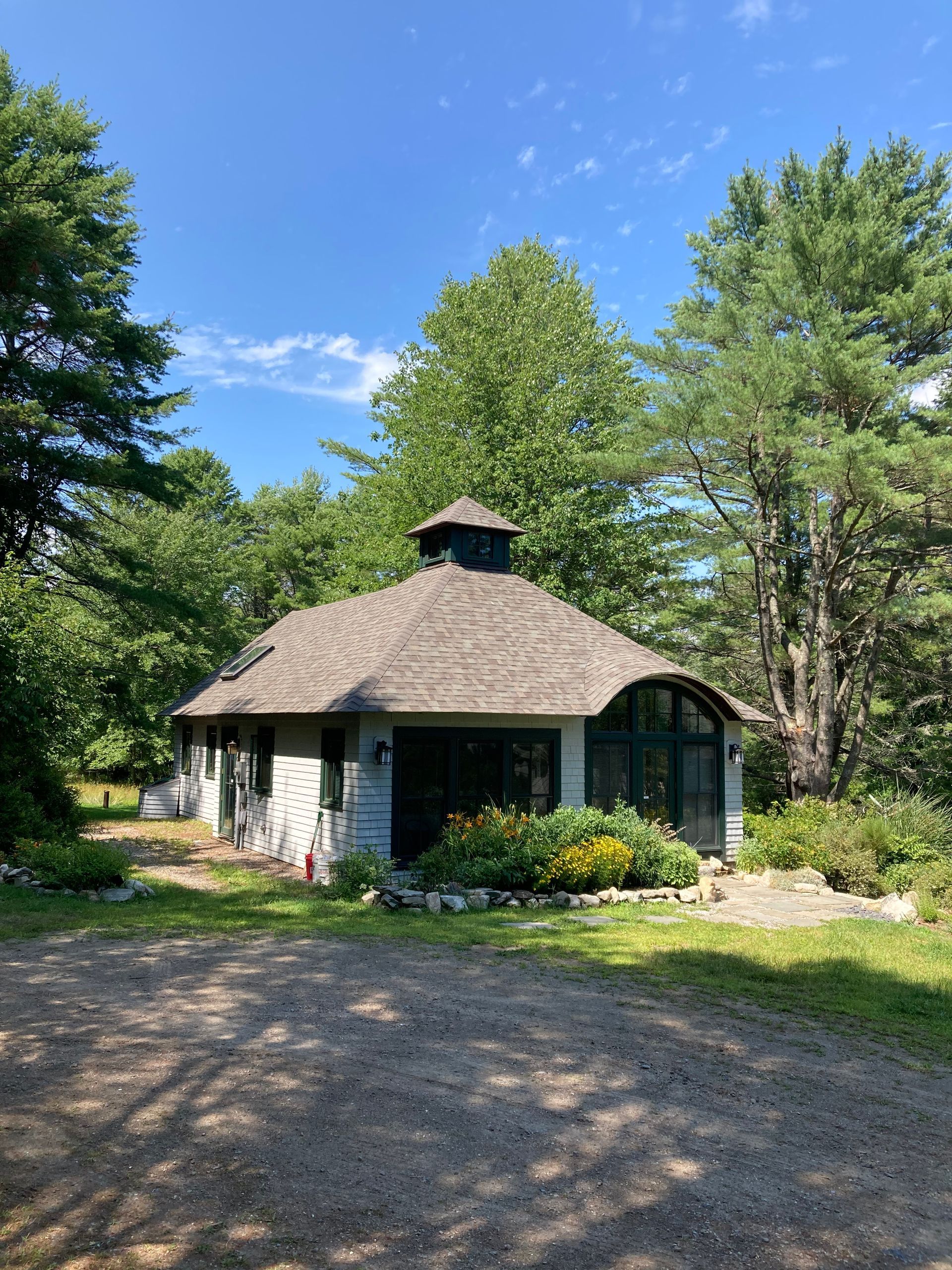 A small house is surrounded by trees on a sunny day.