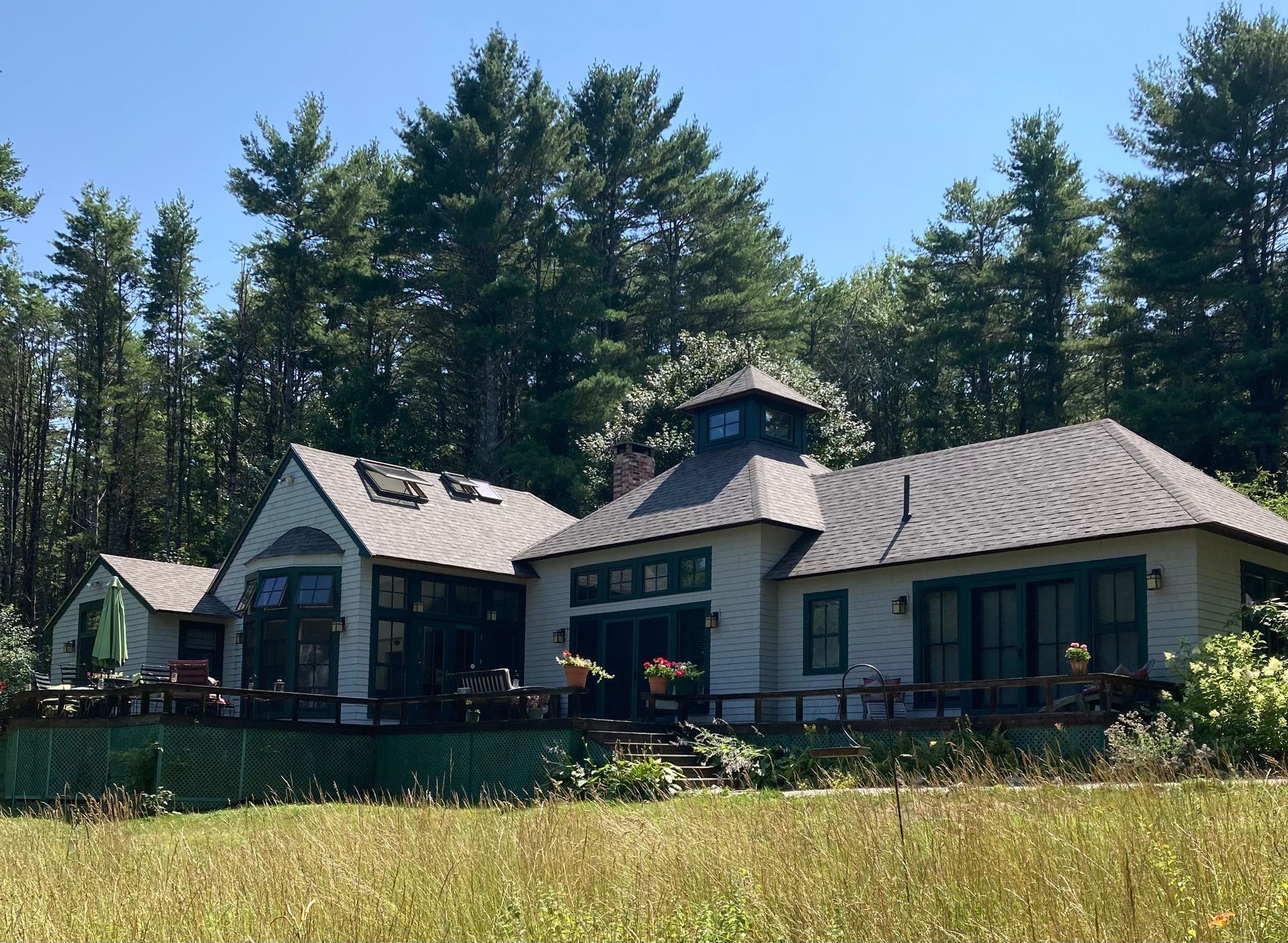 A large white house sits in the middle of a grassy field