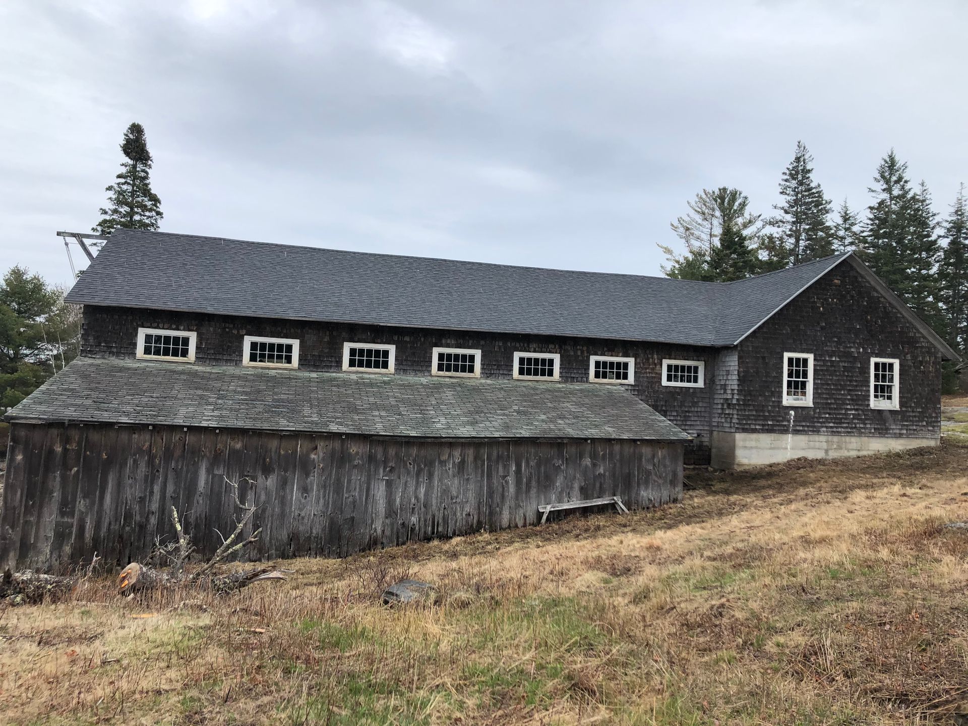 A large barn is sitting in the middle of a grassy field.