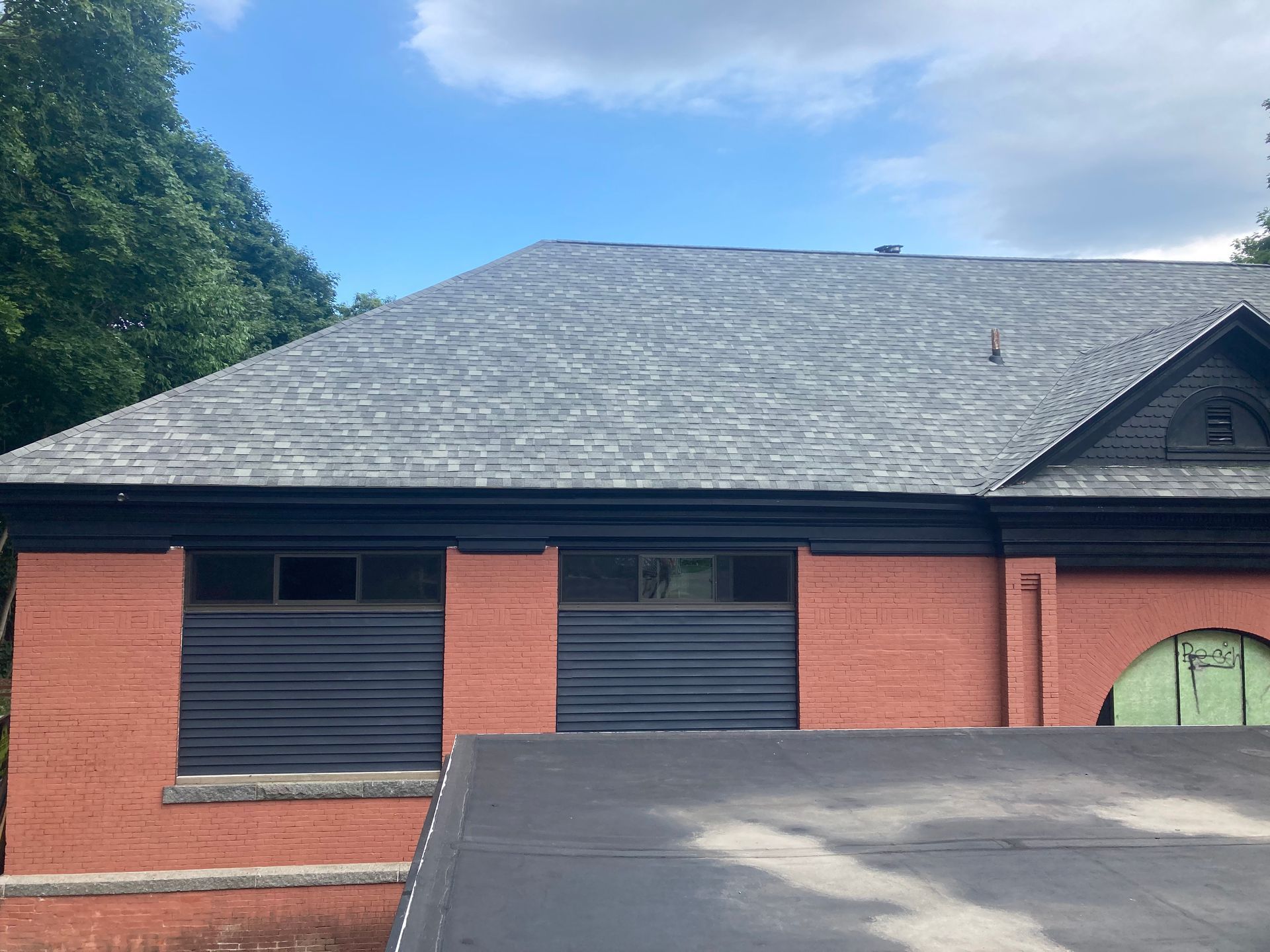 A red brick house with a black garage door and a gray roof.