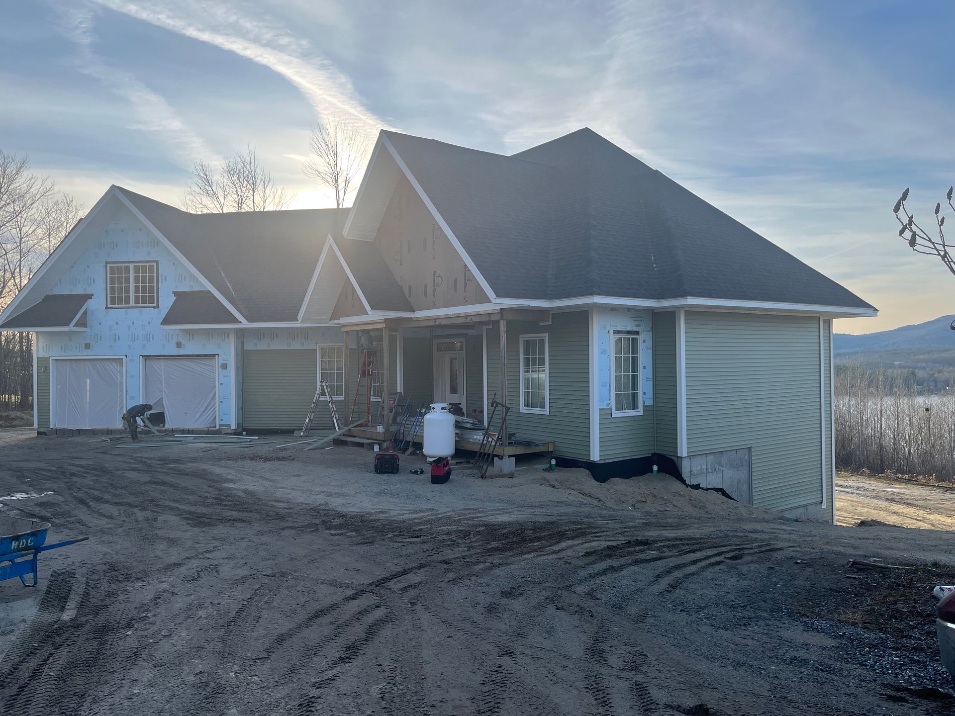 A large house is being built in the middle of a dirt field.