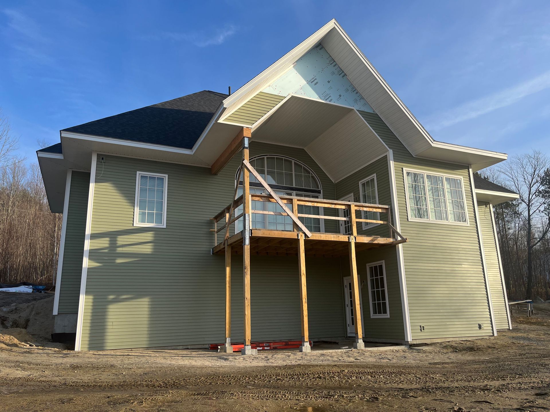 A green house with a balcony on the second floor is being built.
