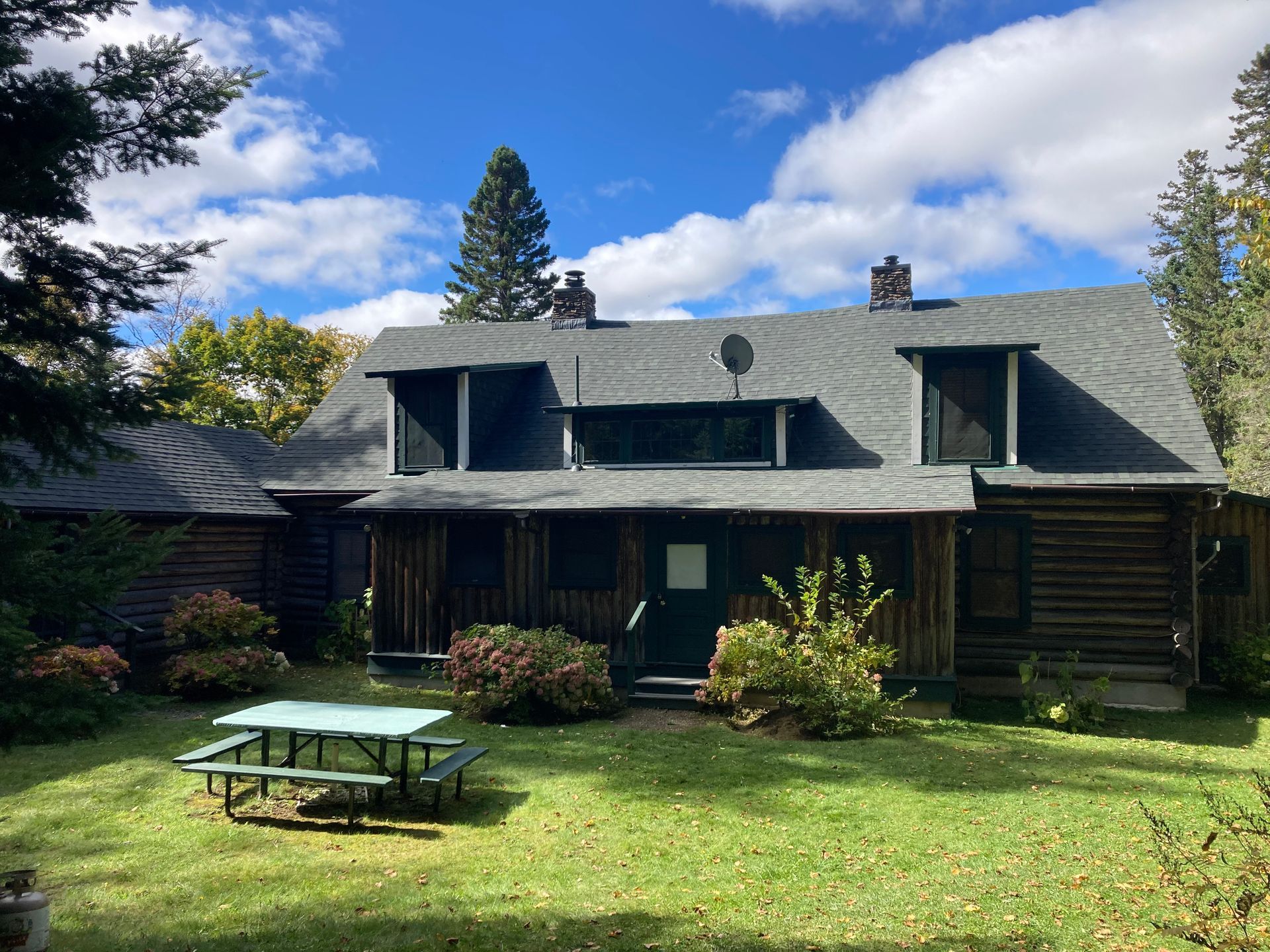 A large log cabin with a picnic table in front of it.