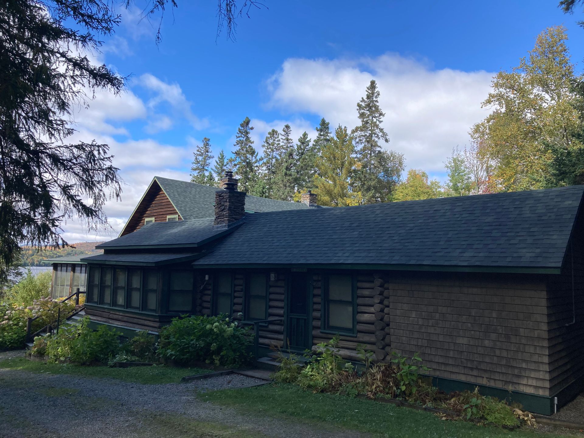 A log cabin with a green roof is surrounded by trees and grass.