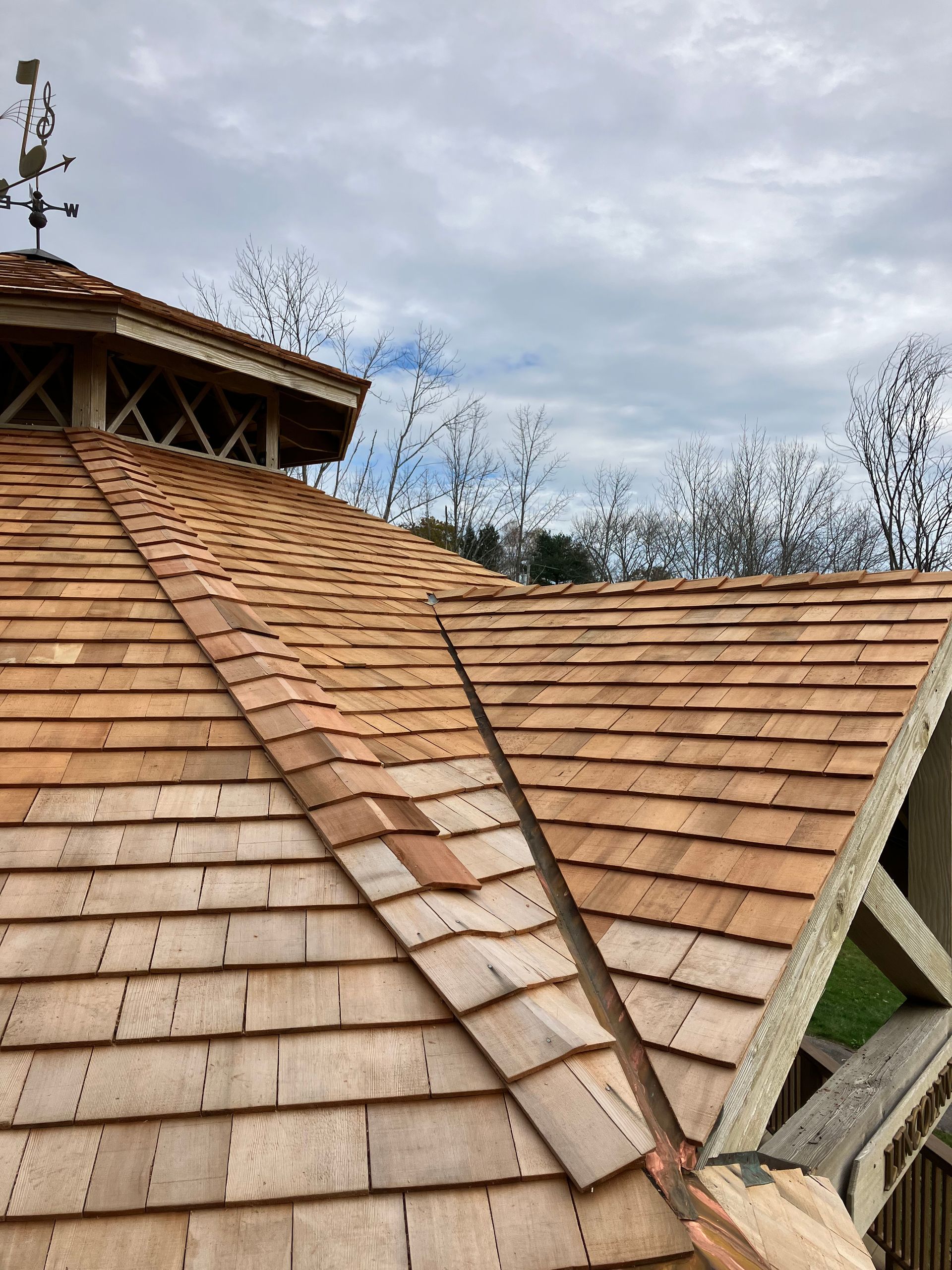 A wooden roof with a weather vane on top of it.