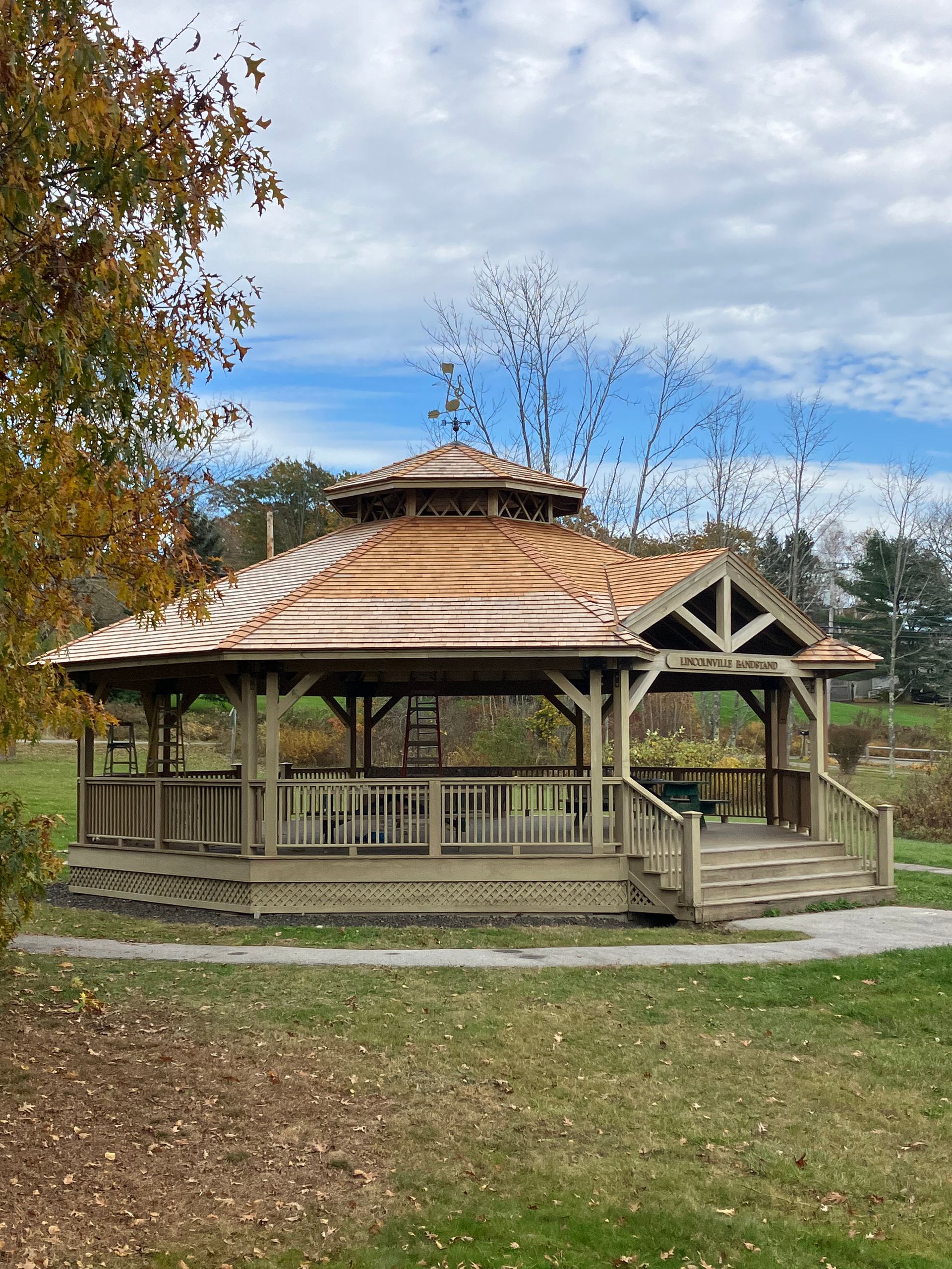 A gazebo is sitting in the middle of a park on a sunny day.