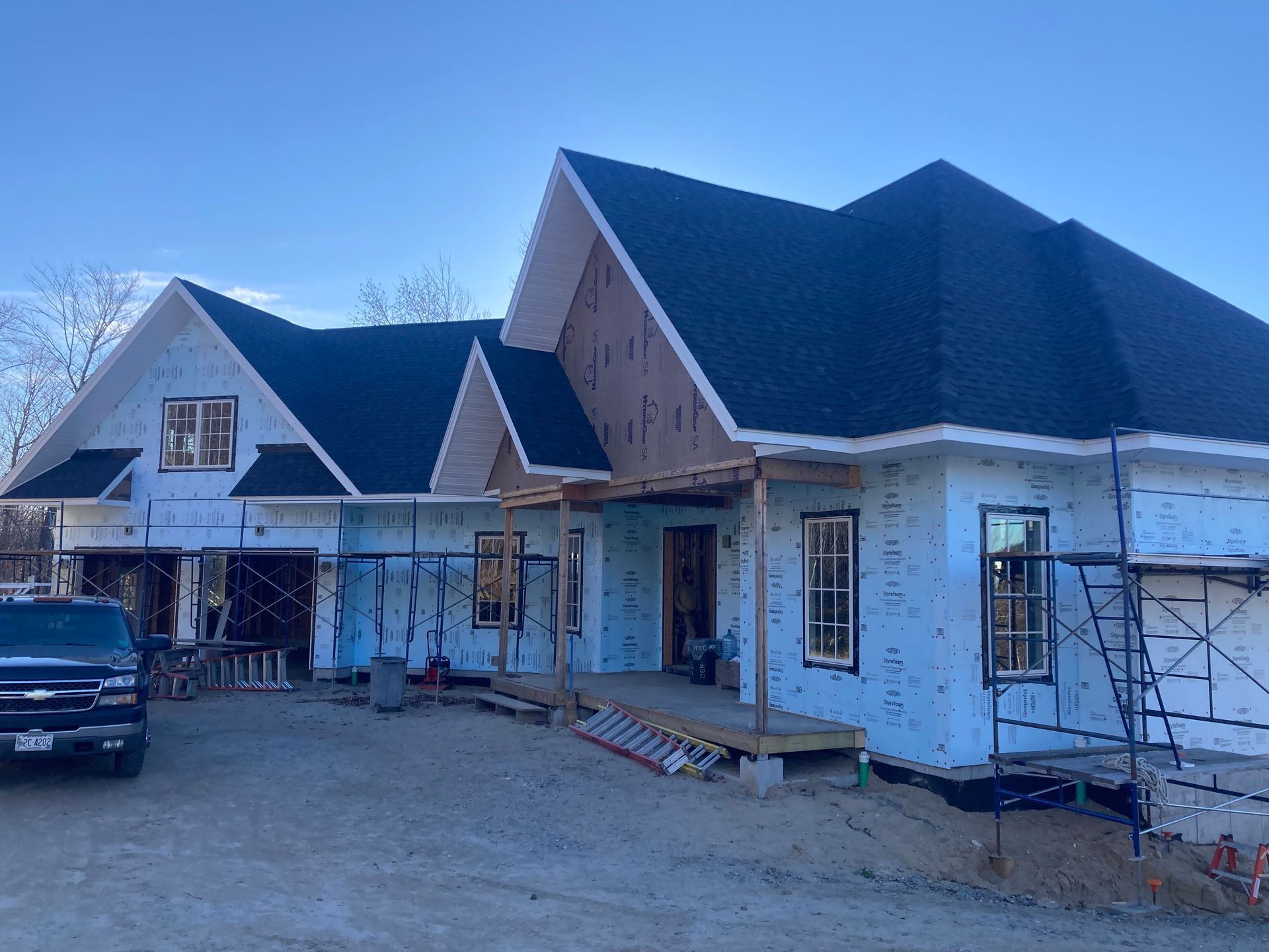 A truck is parked in front of a house under construction.