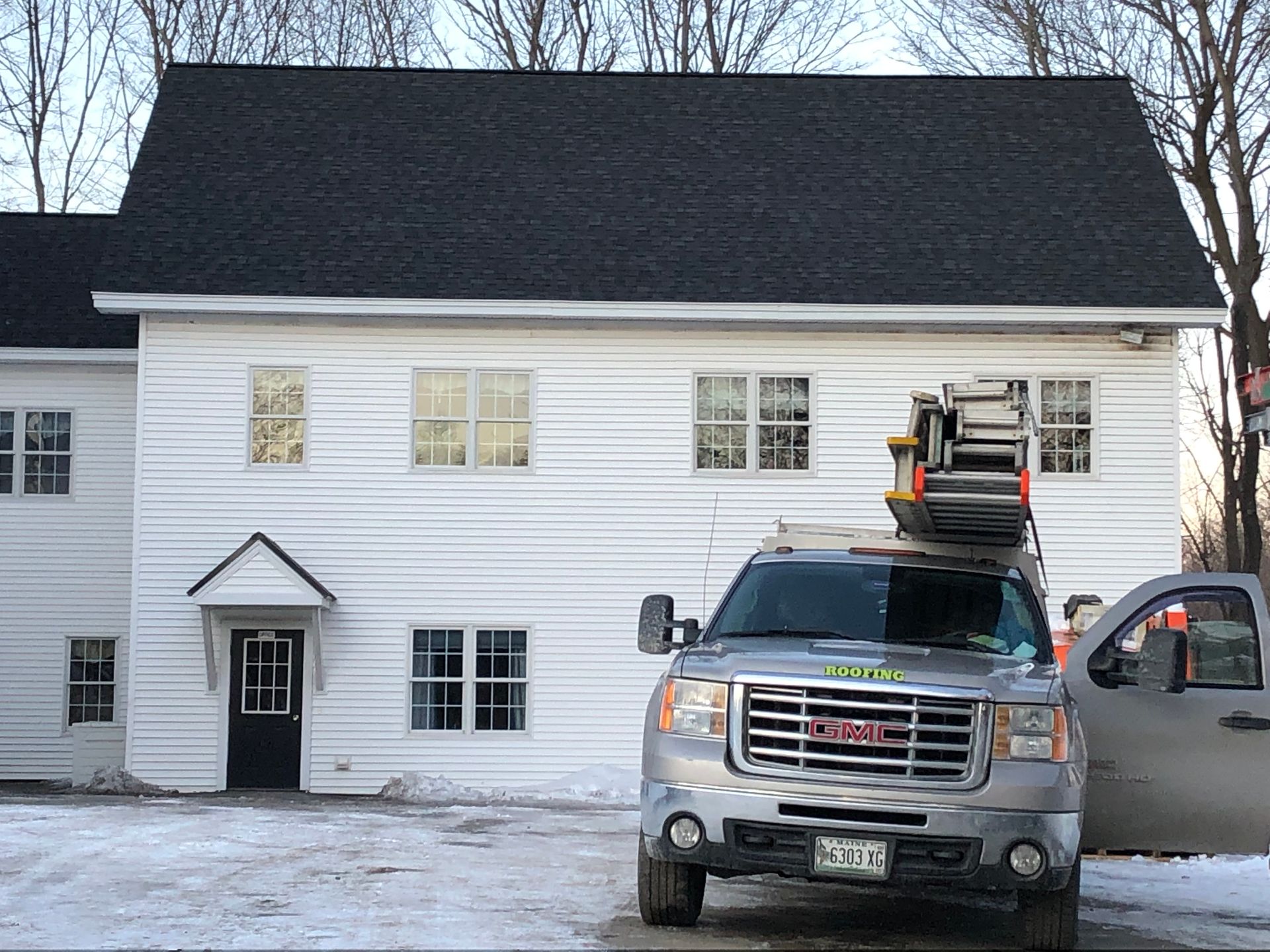 A gmc truck is parked in front of a white house.