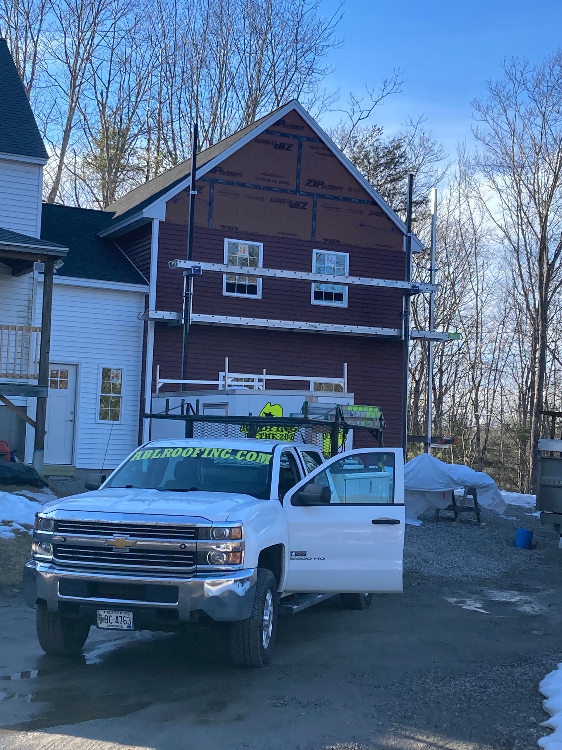 A white truck is parked in front of a red house.