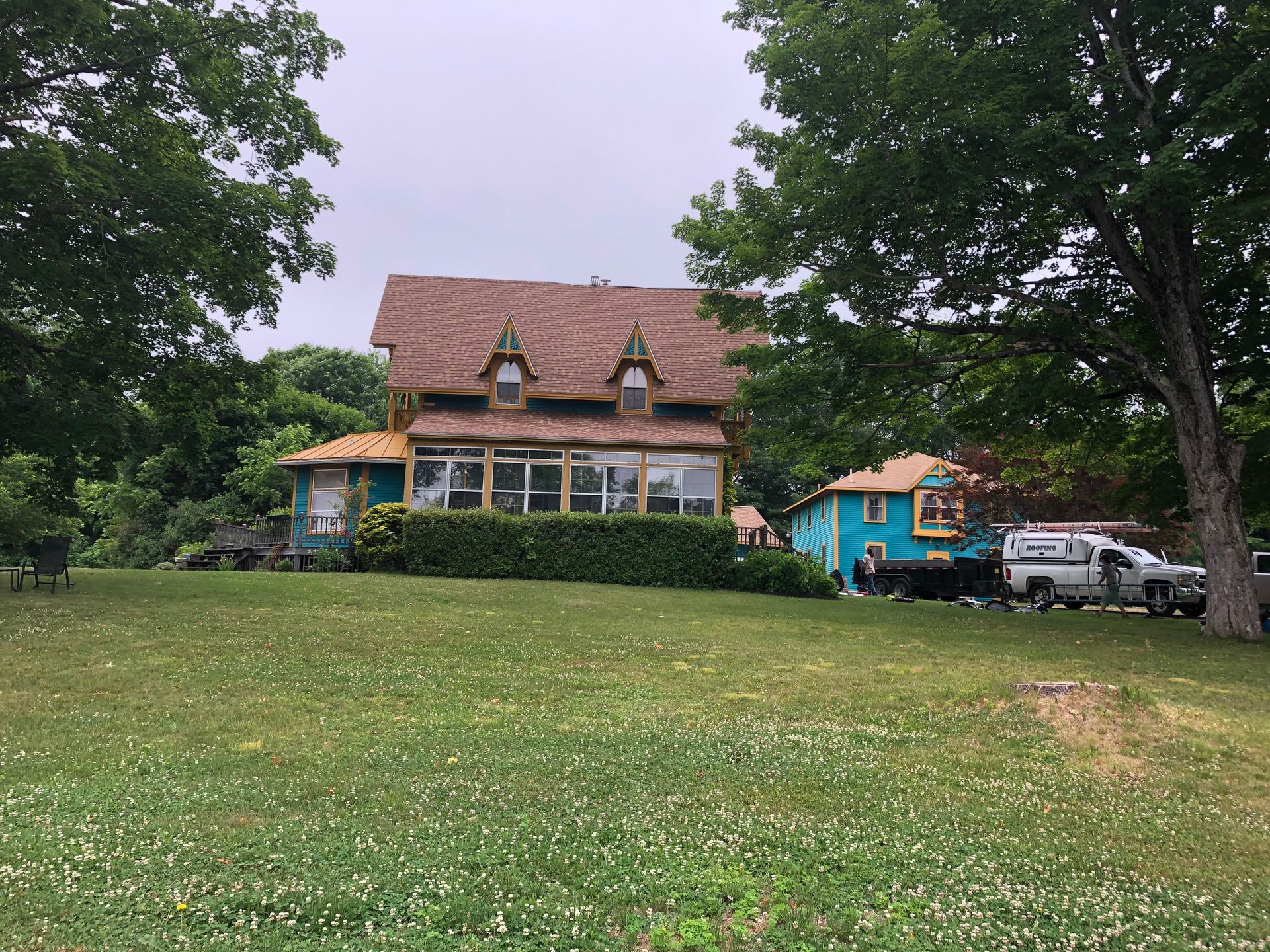 A large house is sitting on top of a lush green hill surrounded by trees.