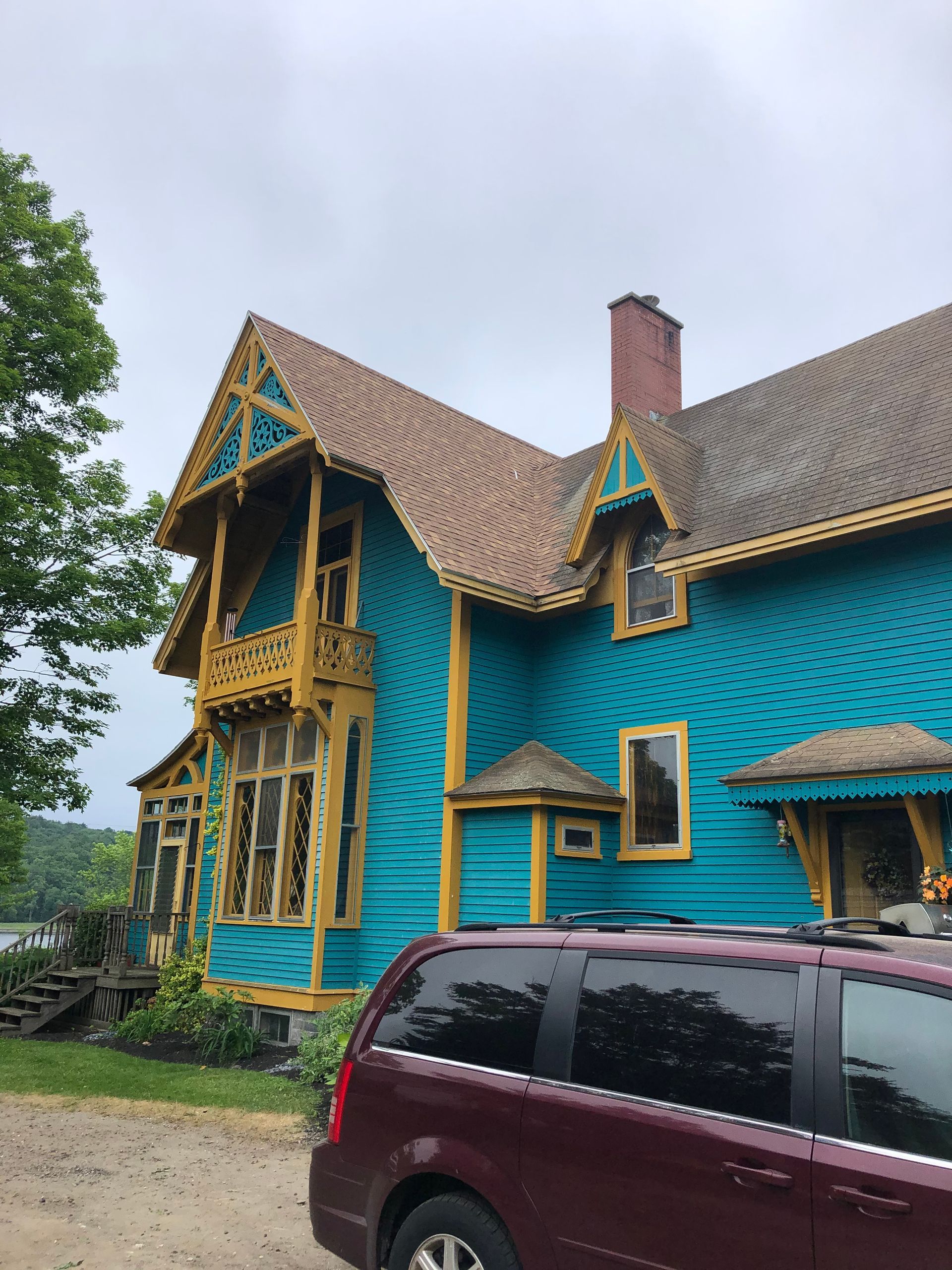 A blue house with a red van parked in front of it