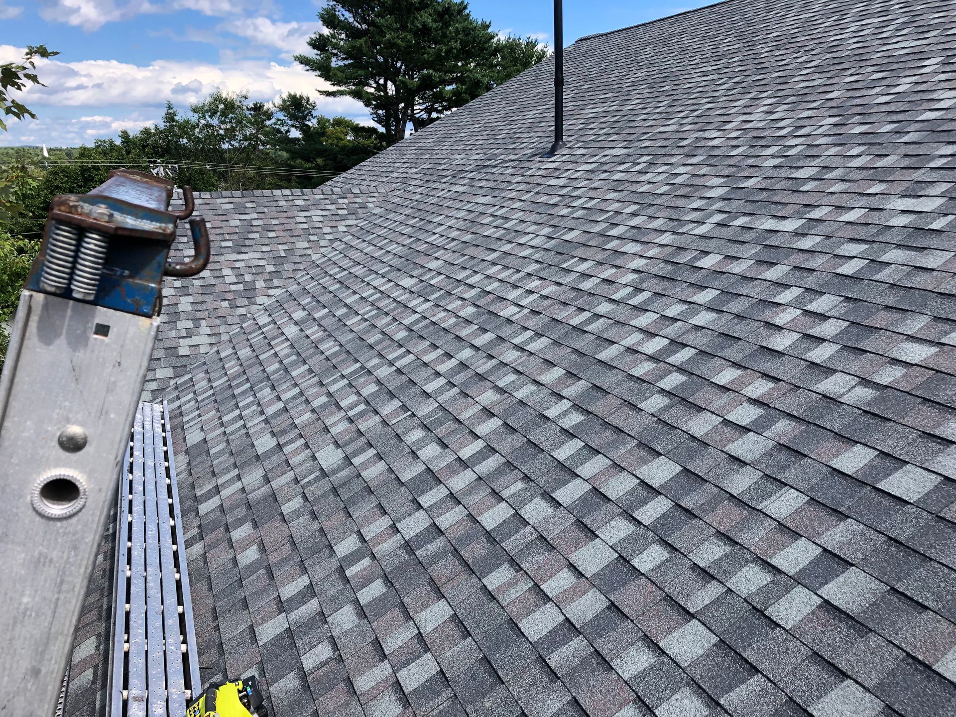 A ladder is sitting on top of a roof next to a chimney.