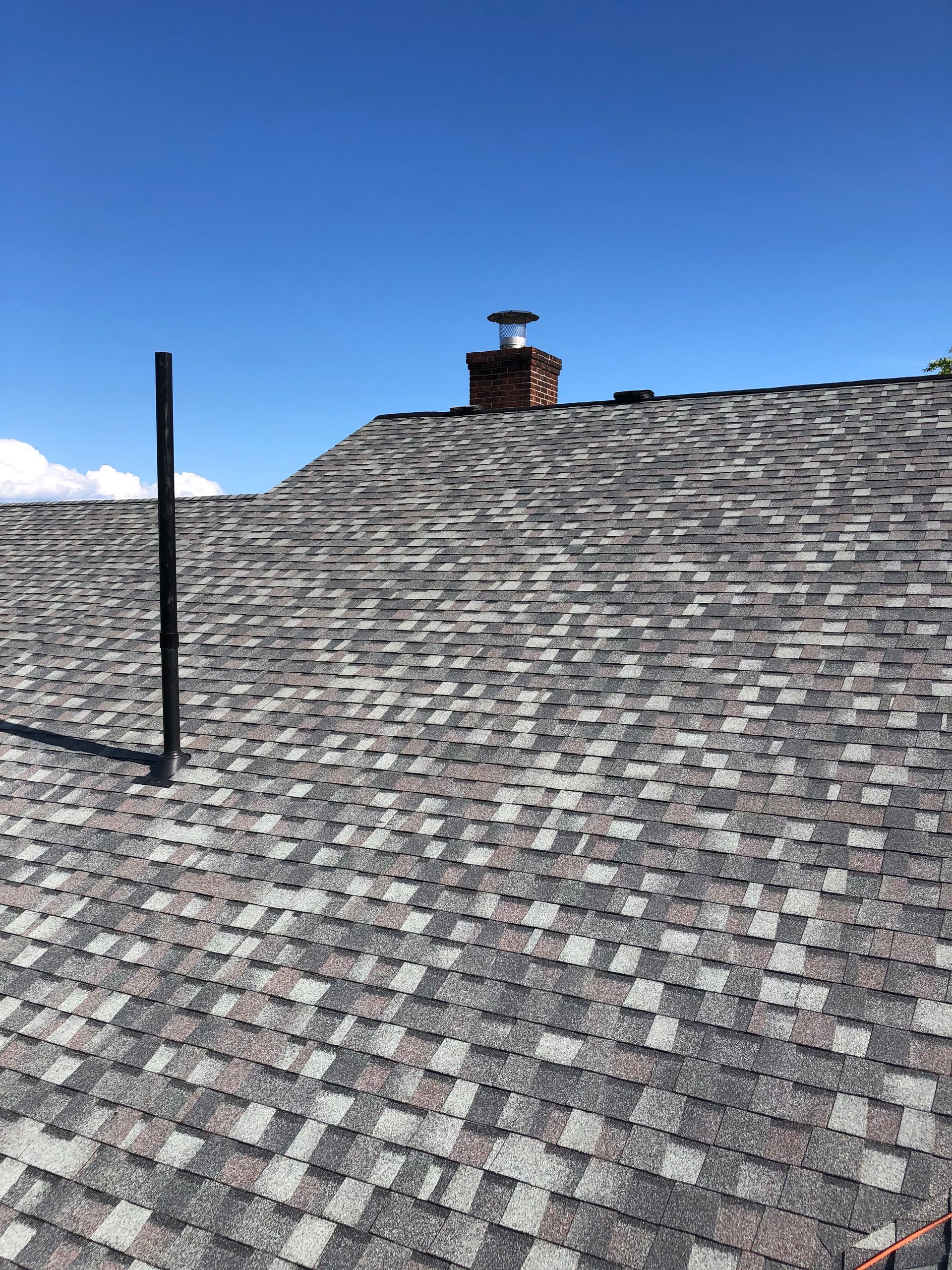 A roof with a chimney on top of it and a blue sky in the background.