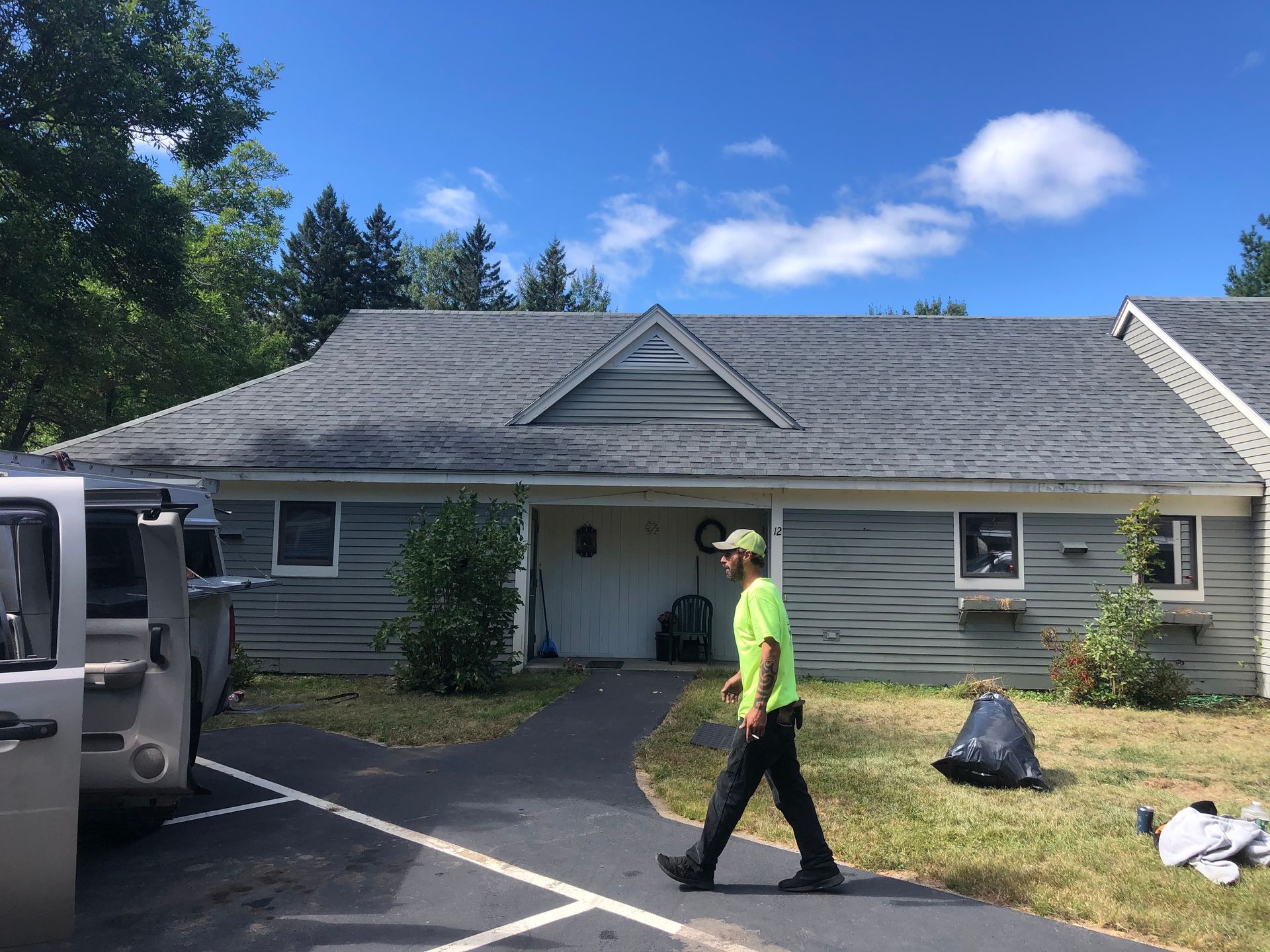 A man is walking in front of a house on a sunny day.